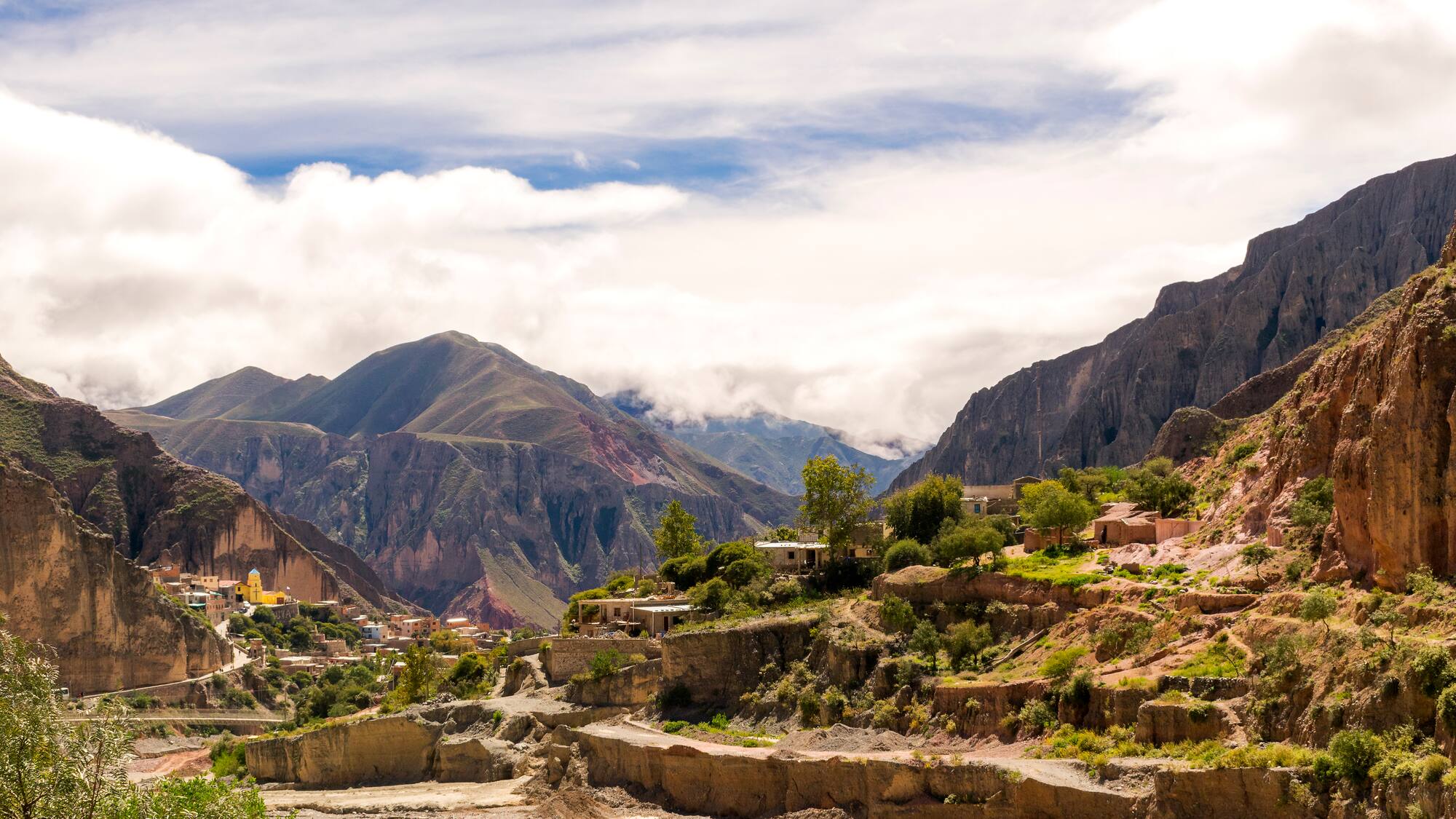 a town on a hillside with mountains in the background