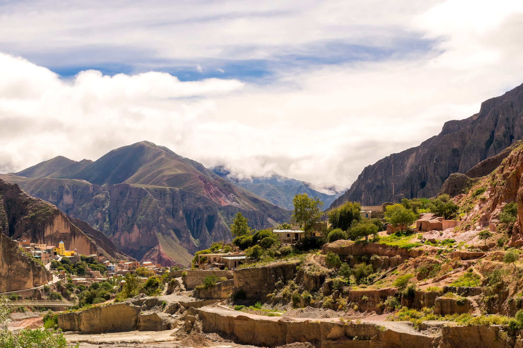 a town on a hillside with mountains in the background