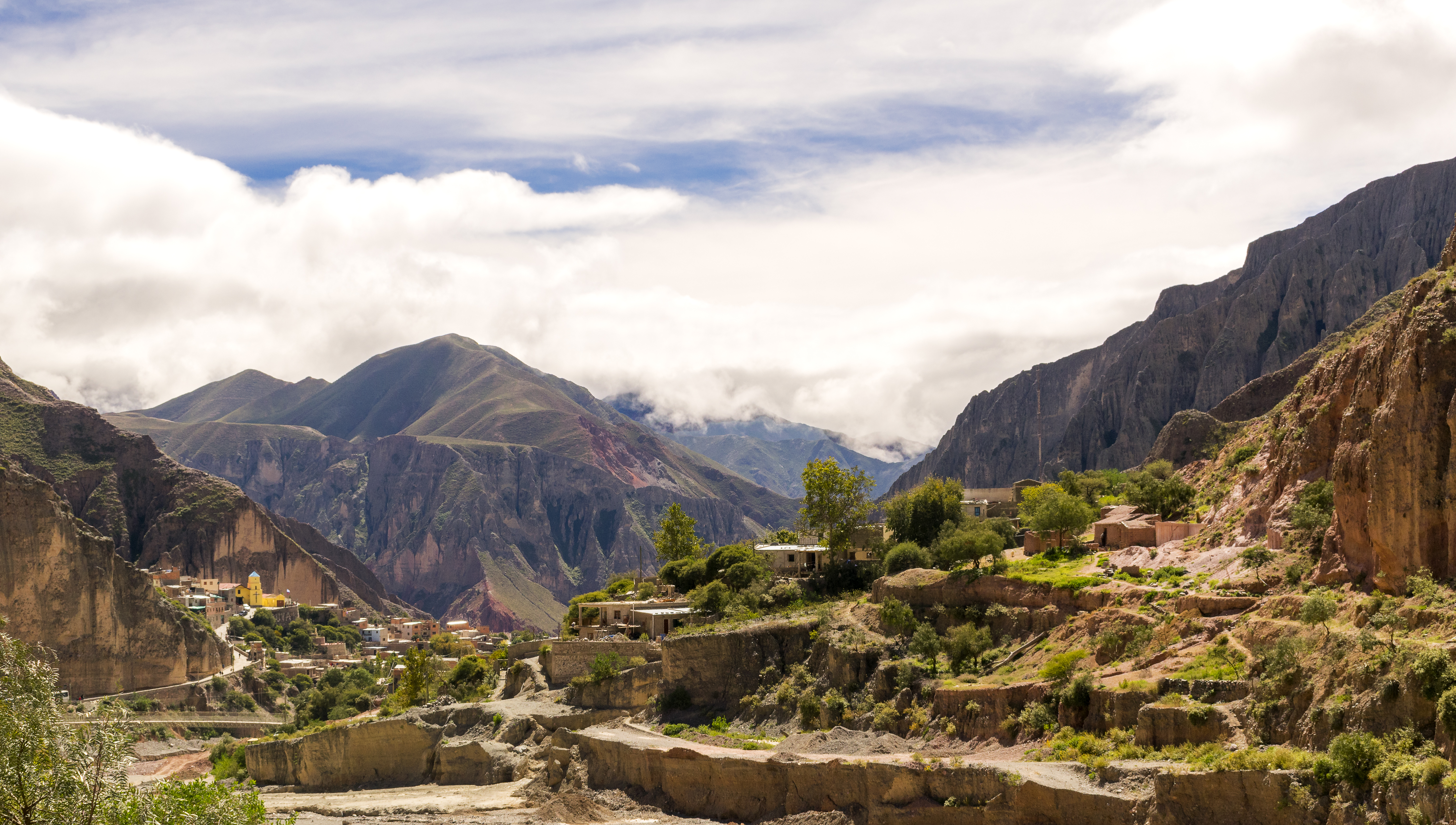 a town on a hillside with mountains in the background