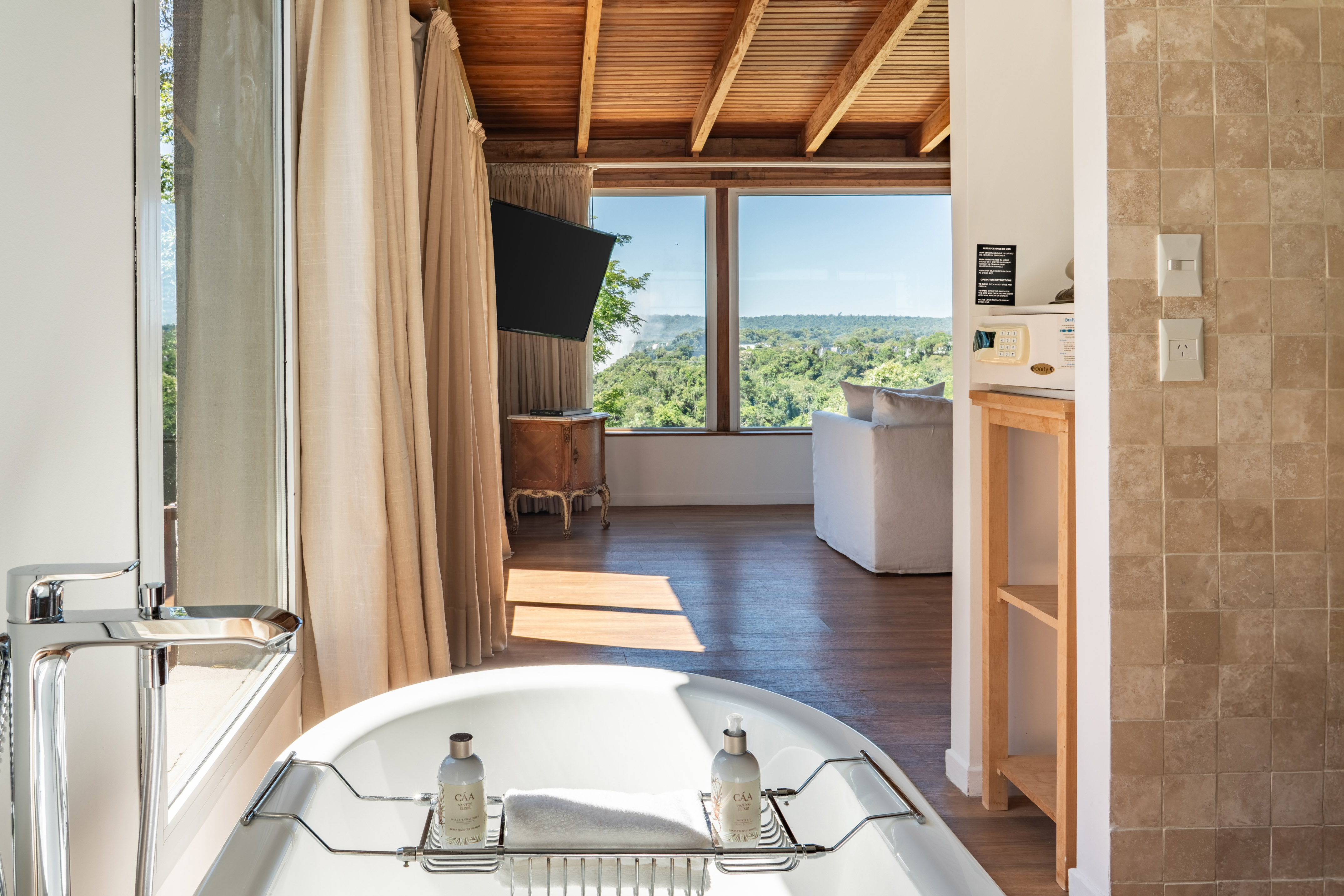 Luxury hotel suite: freestanding tub, modern faucet, panoramic jungle view.