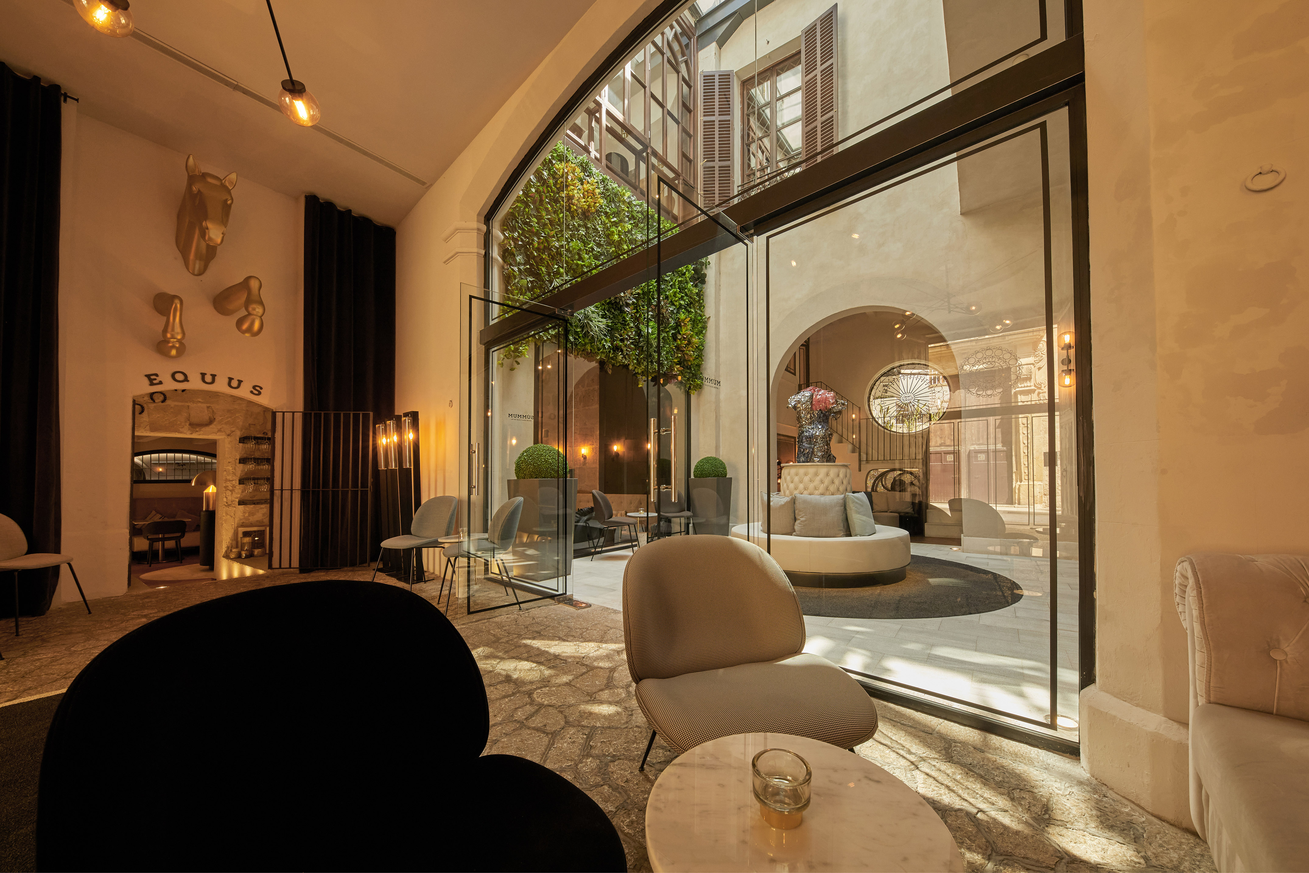 Modern hotel lobby overlooking green courtyard, sleek furniture, Equus decor.