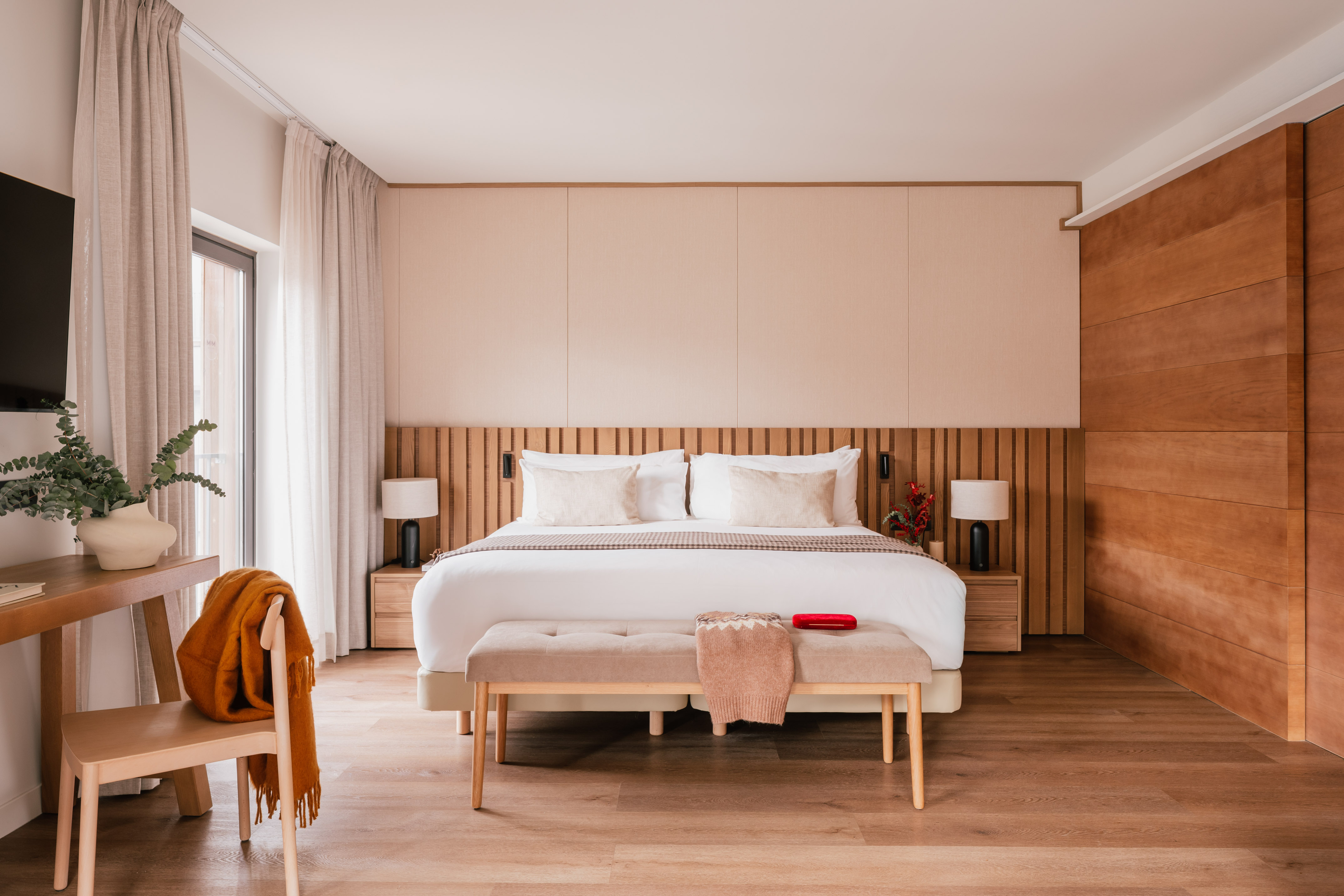 Contemporary bedroom with king bed, wooden slat headboard, and neutral decor.