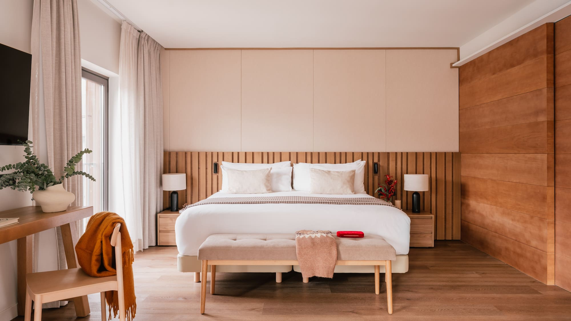 Contemporary bedroom with king bed, wooden slat headboard, and neutral decor.