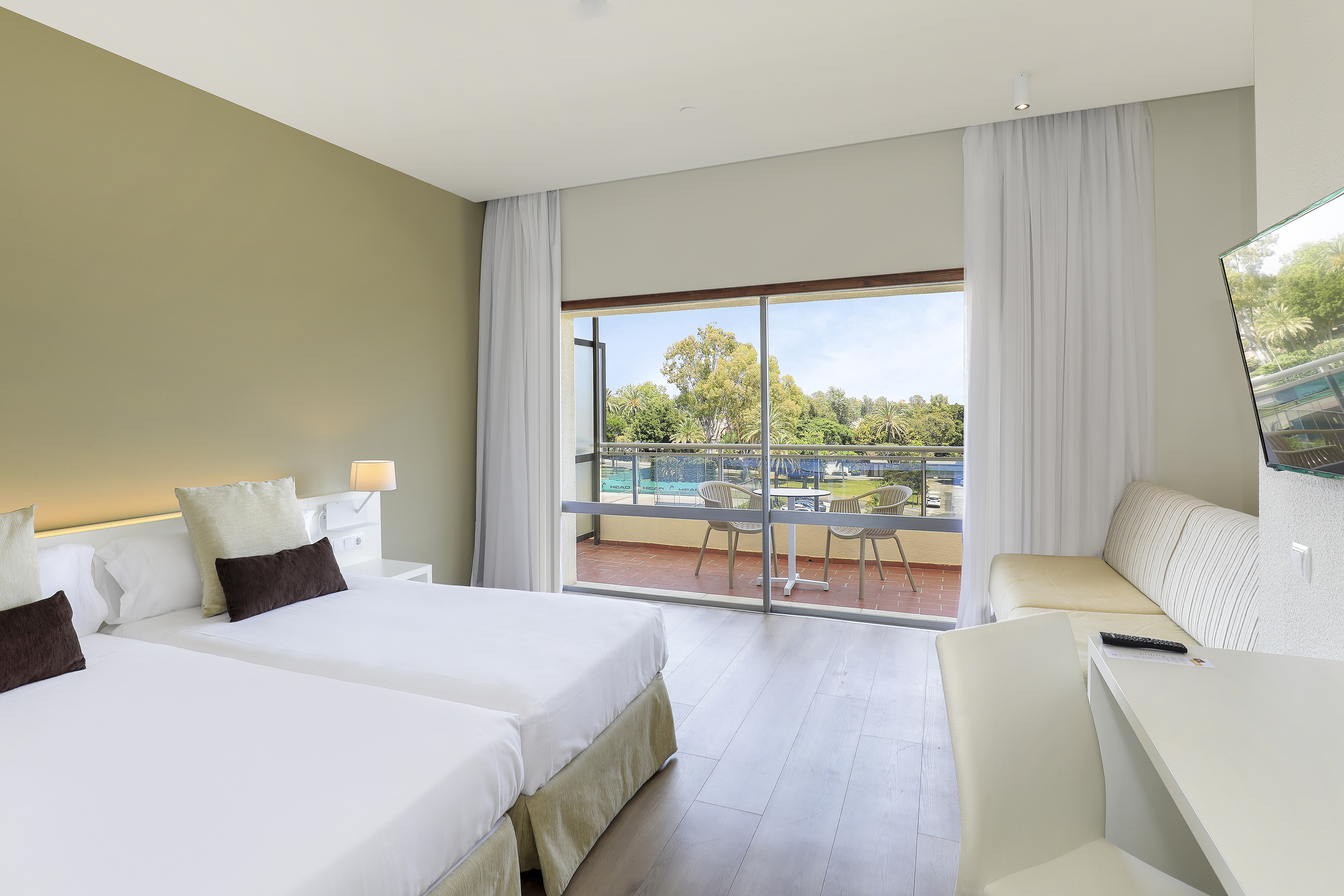 Hotel room with twin beds, private balcony, and pool view.