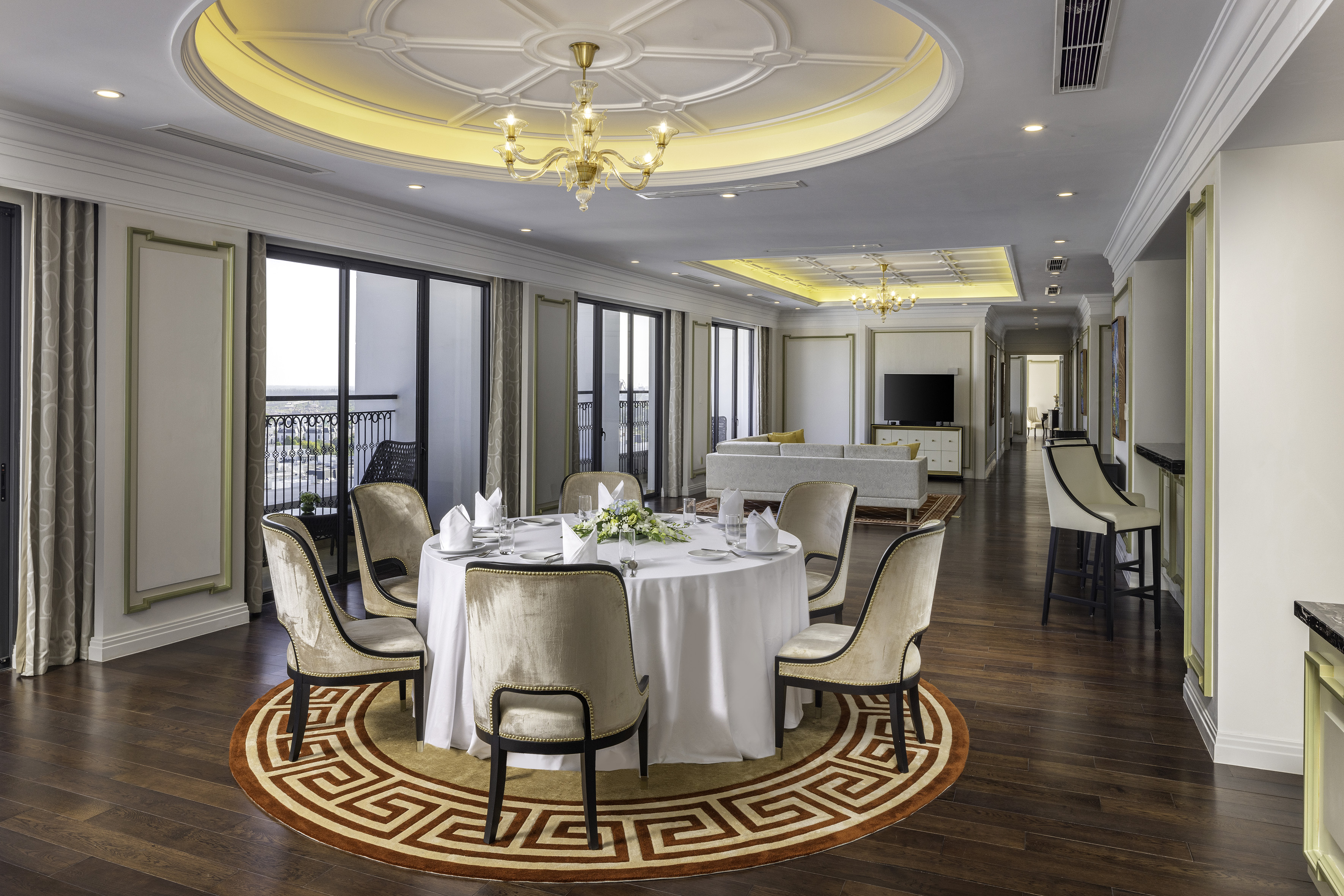 Luxury suite dining area with velvet chairs, round table, hardwood, city view.