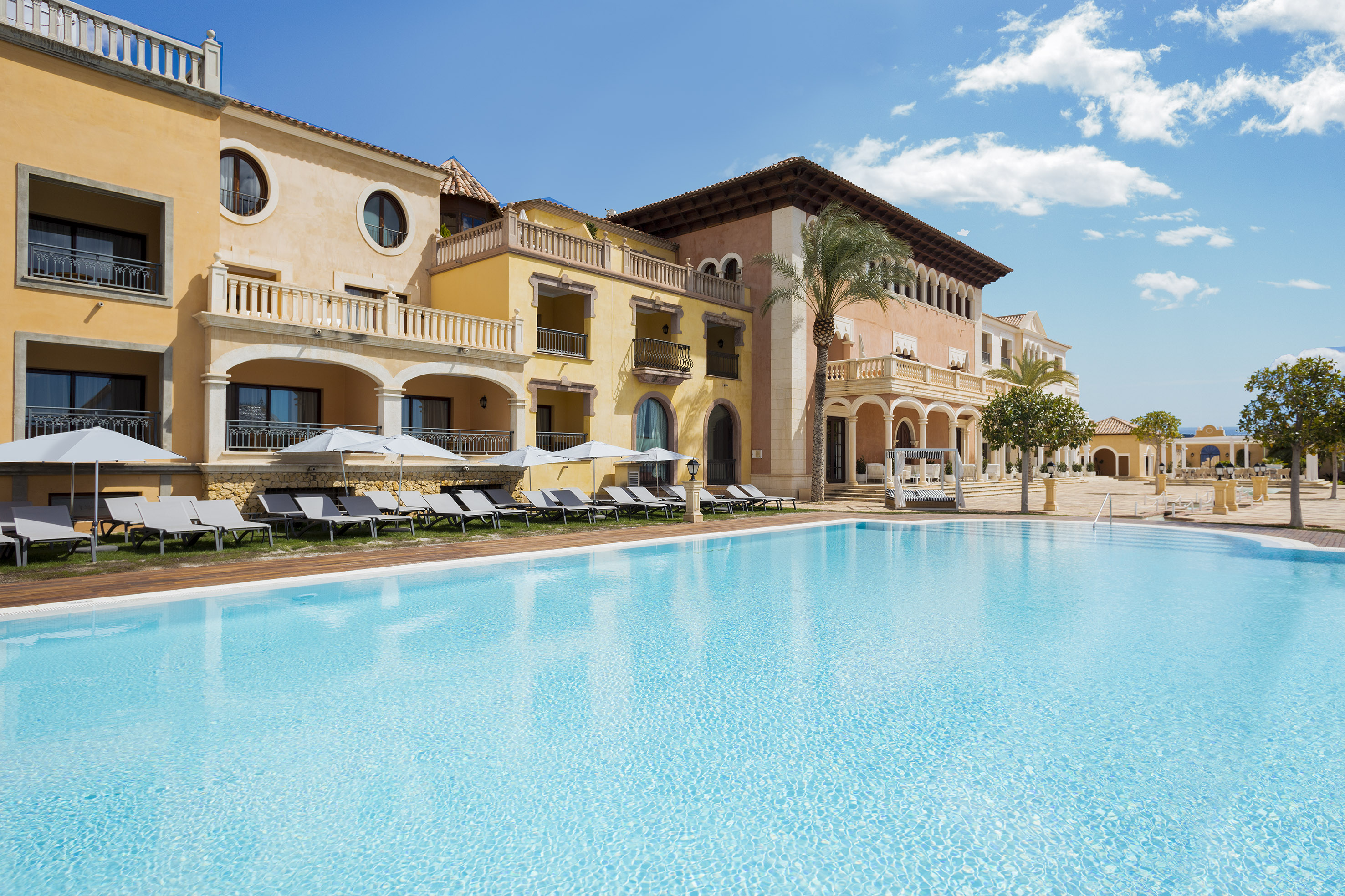 a swimming pool with a building and lounge chairs