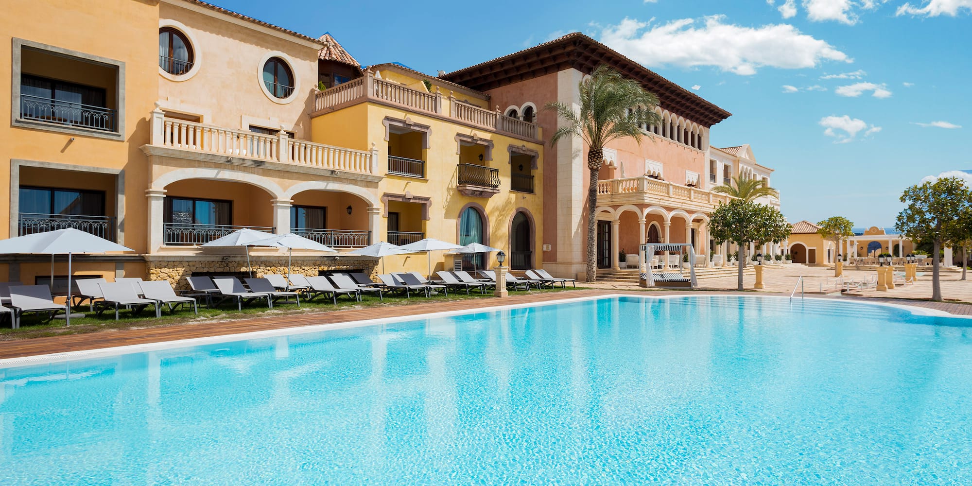 a swimming pool with a building and lounge chairs