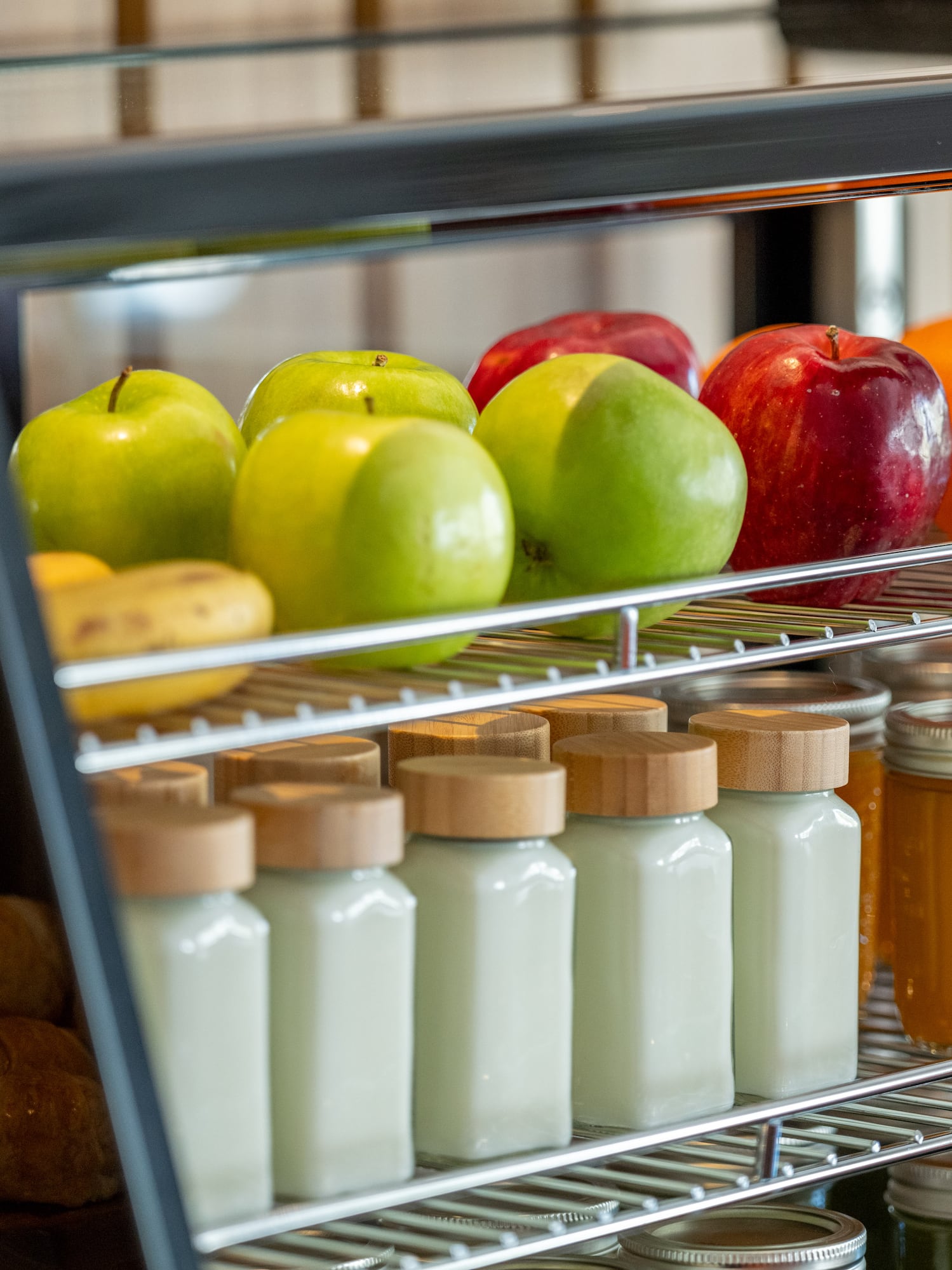 a glass display case with fruits and jars on shelves