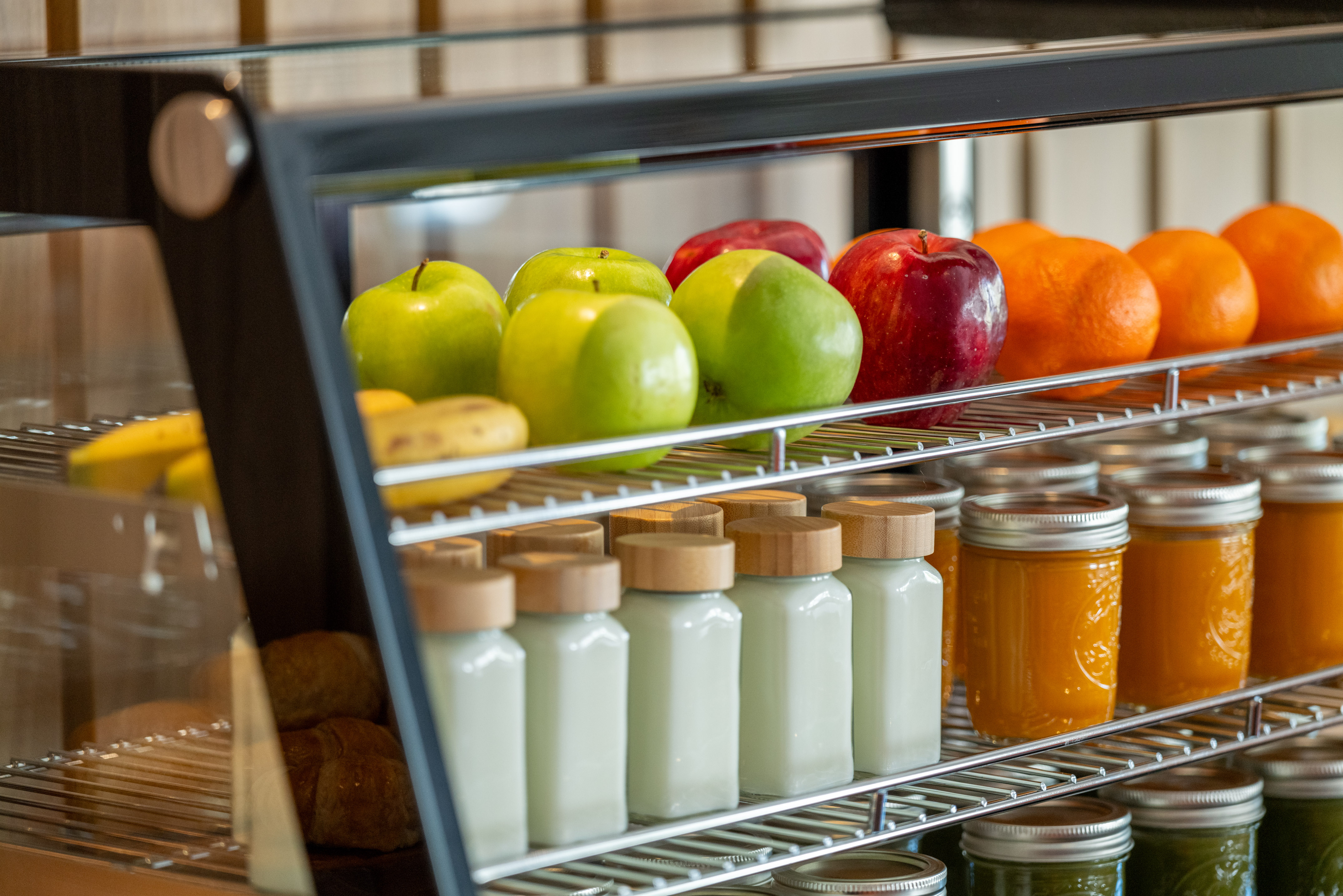 Healthy food display with fresh apples, oranges, bottled drinks, and pastries.