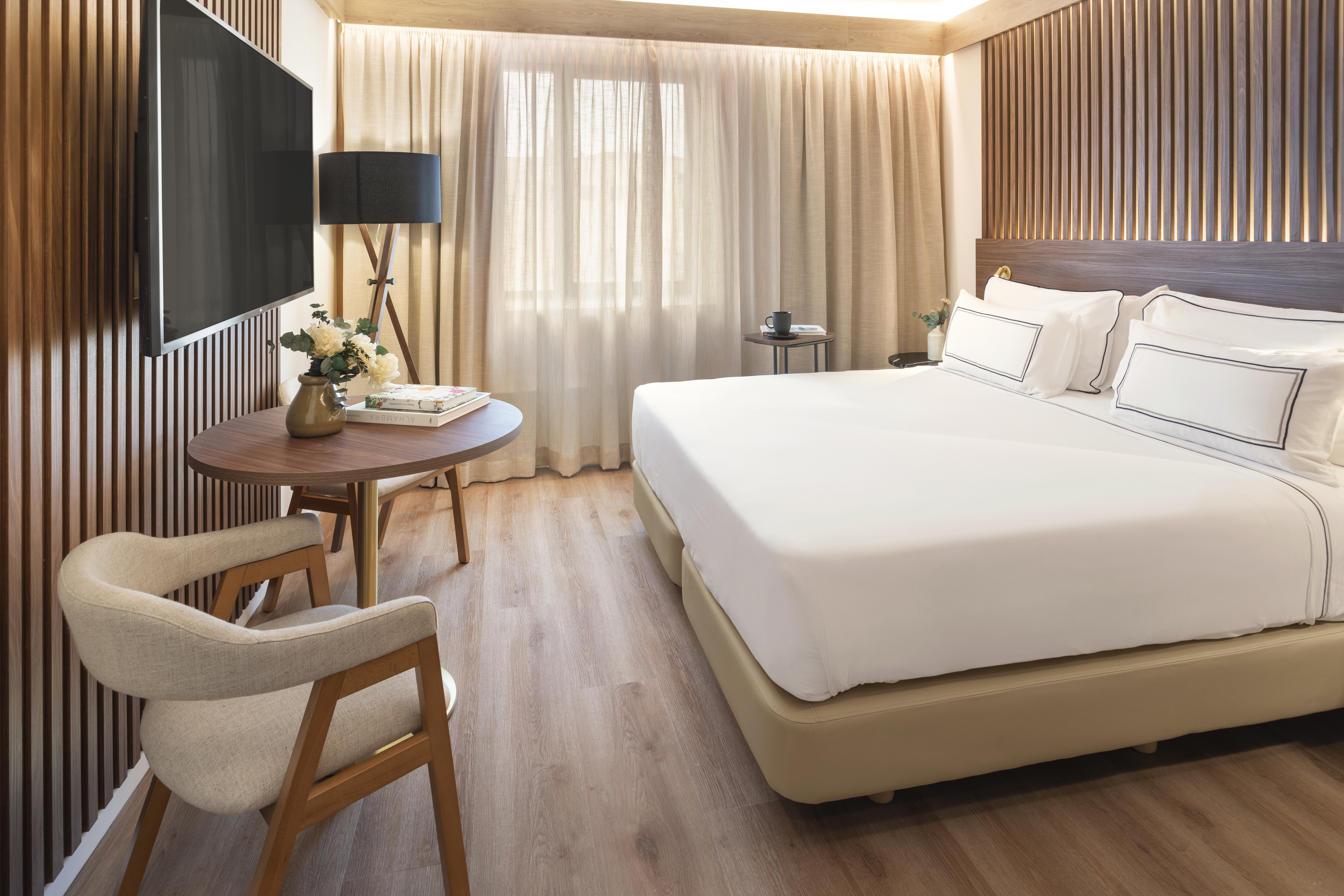 Elegant modern hotel room with queen bed, wood slat wall, TV, and bright window.