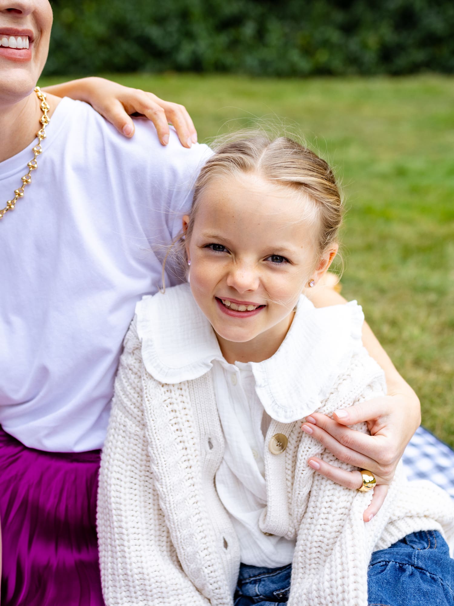 a woman and a girl sitting on a blanket