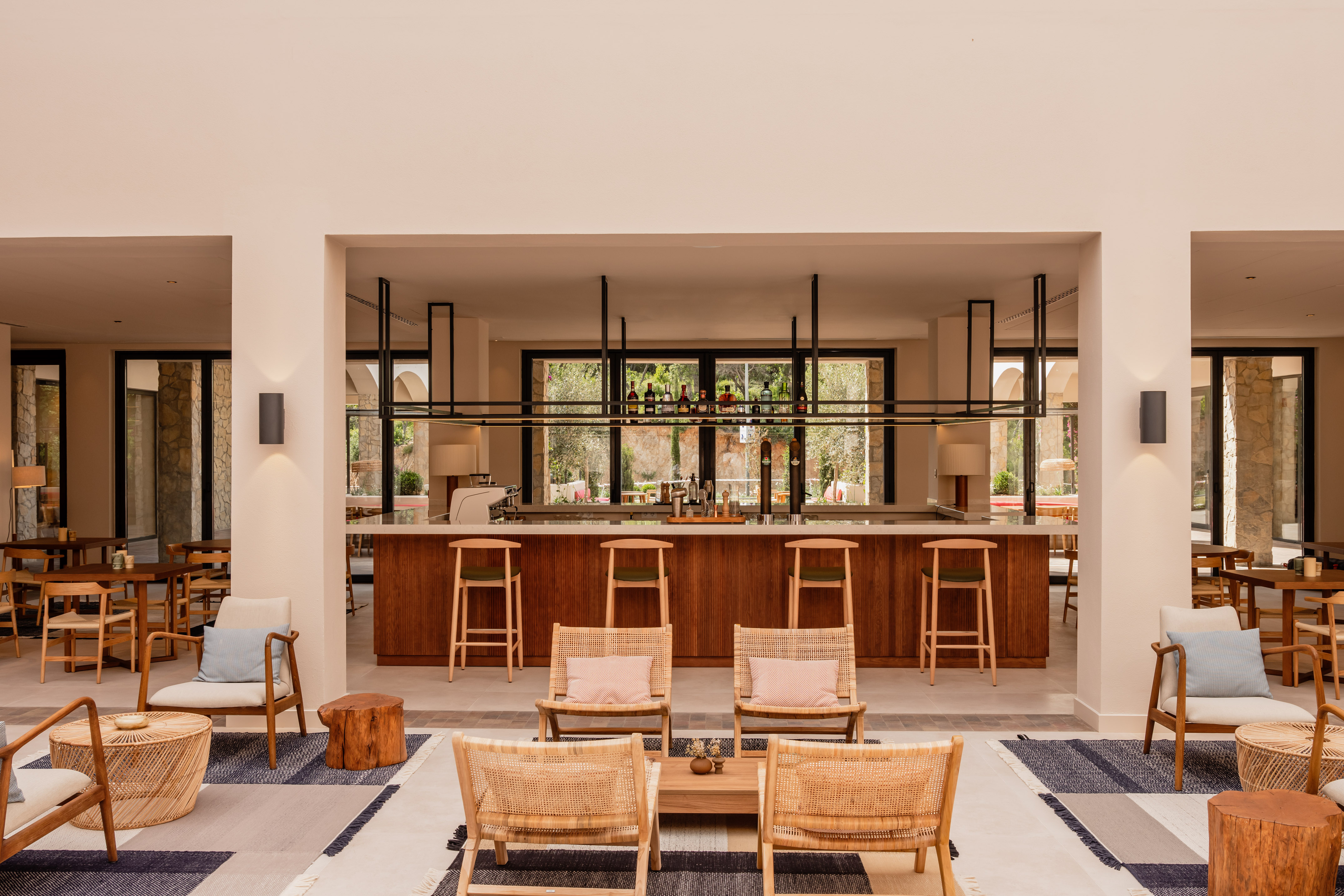 Contemporary hotel lounge with a wooden bar, barstools, and comfortable seating.