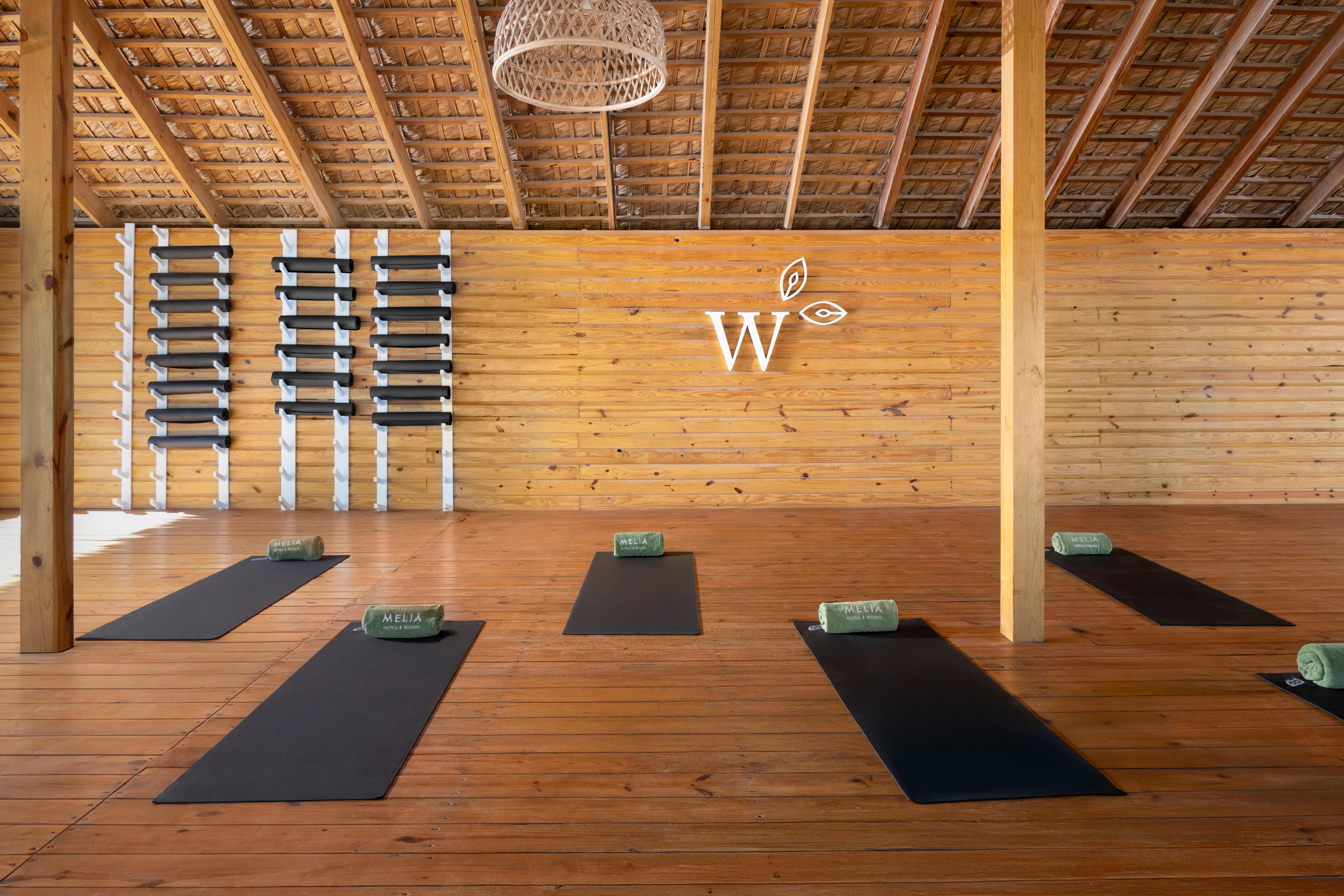 Meliá resort yoga studio with wooden floor, thatched roof, and yoga mats.