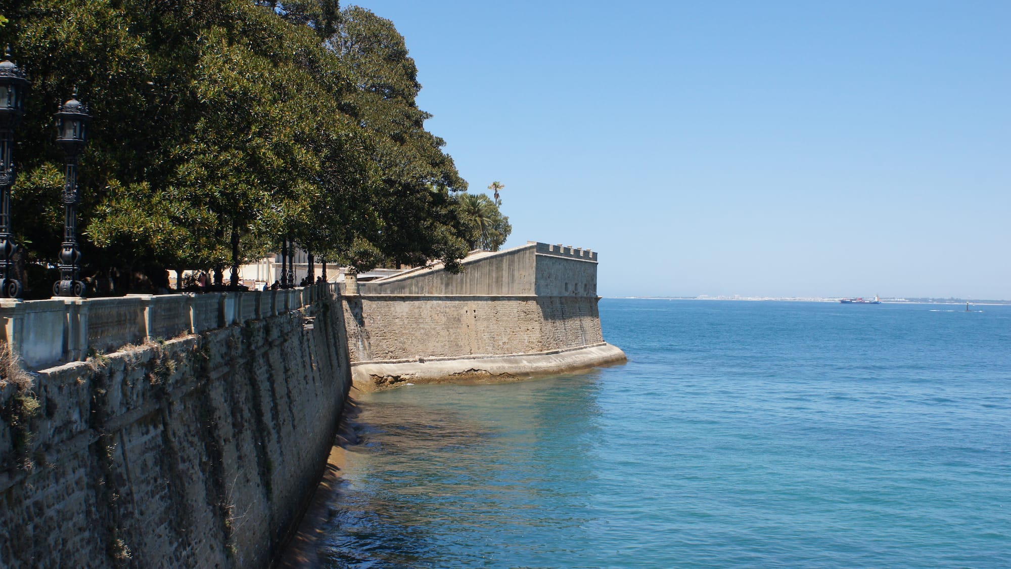 a stone wall next to a body of water