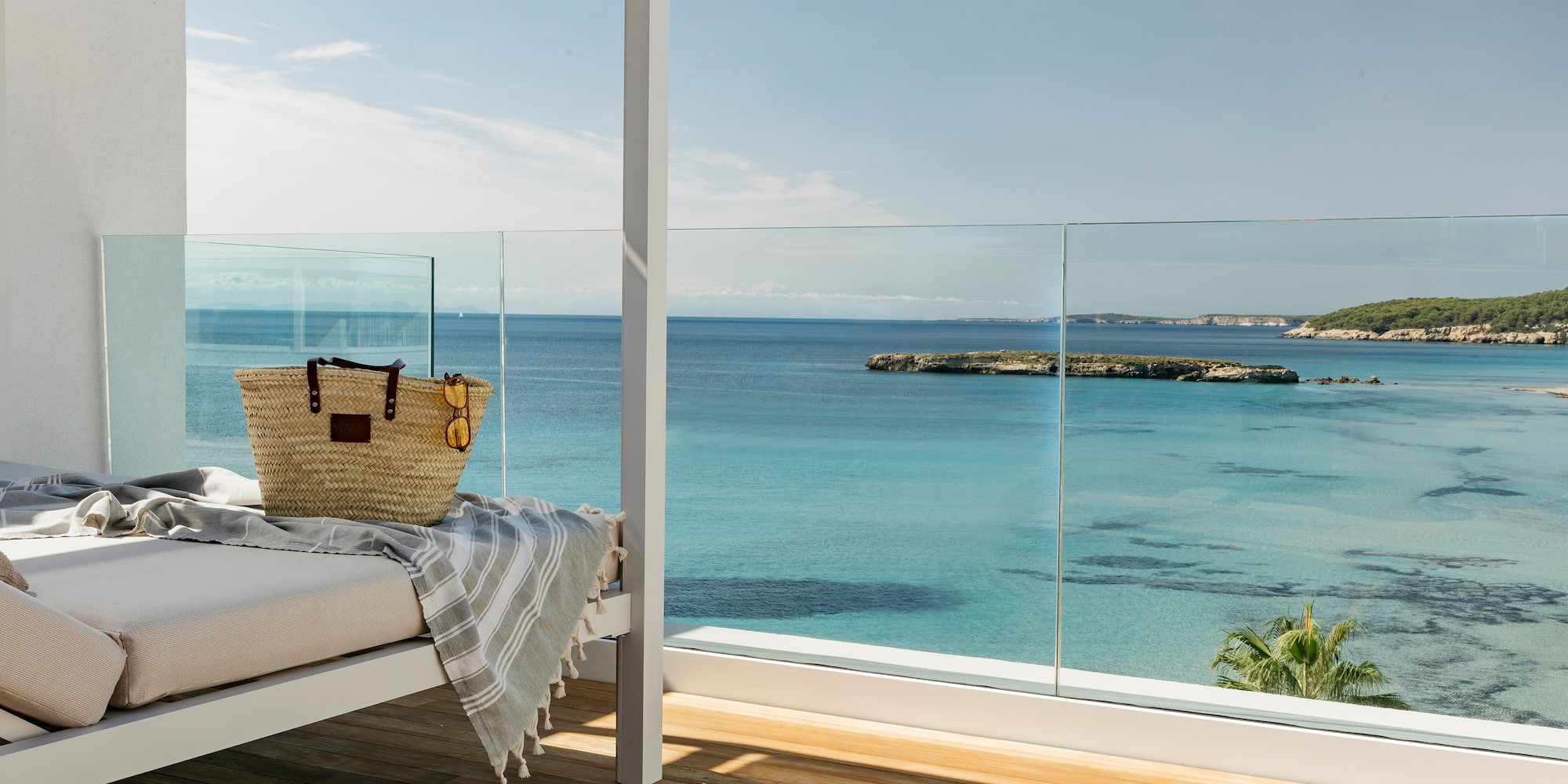 a bed with a blanket and a bag on it overlooking the ocean
