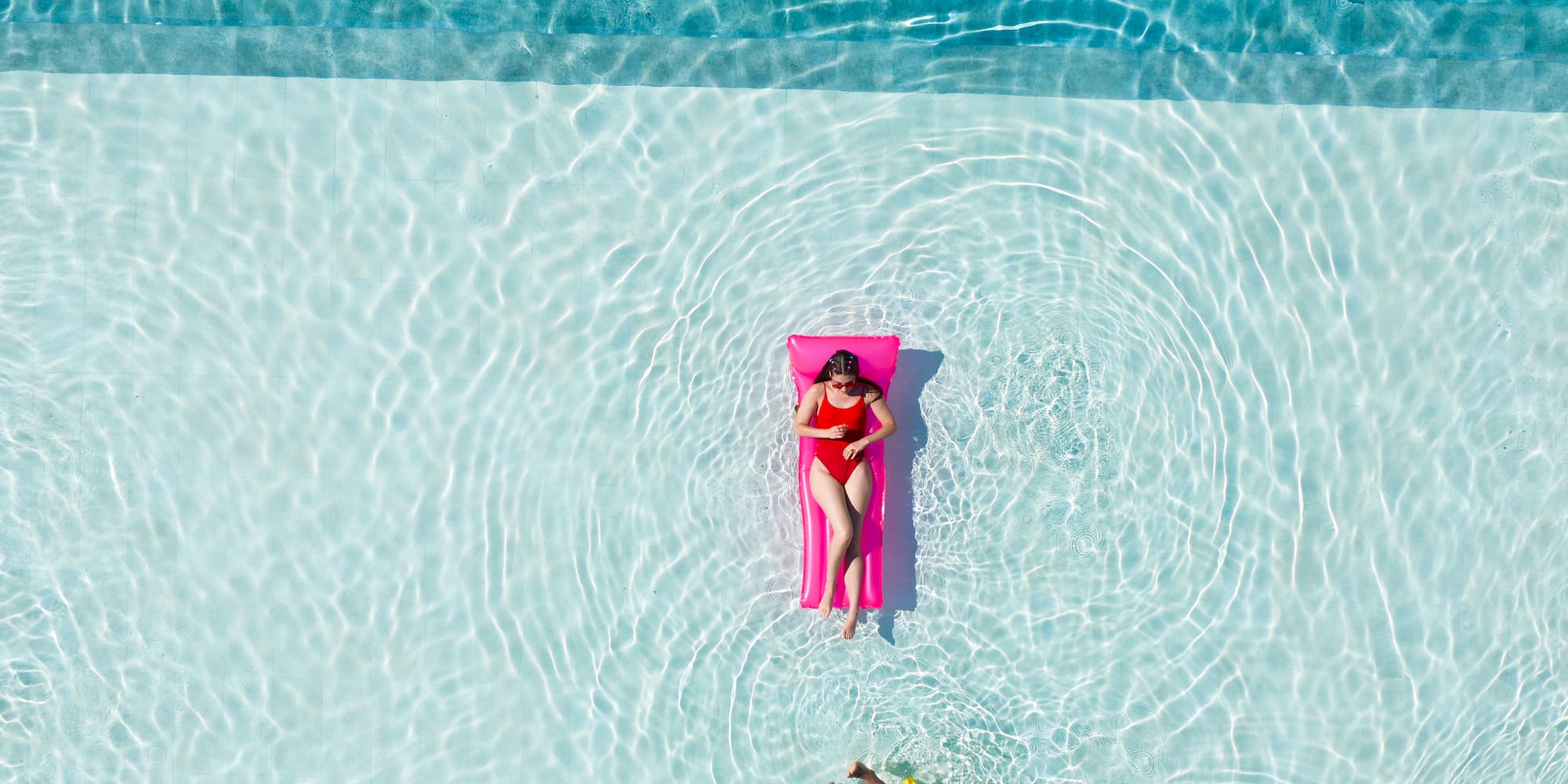 a person floating on a pink float in a pool