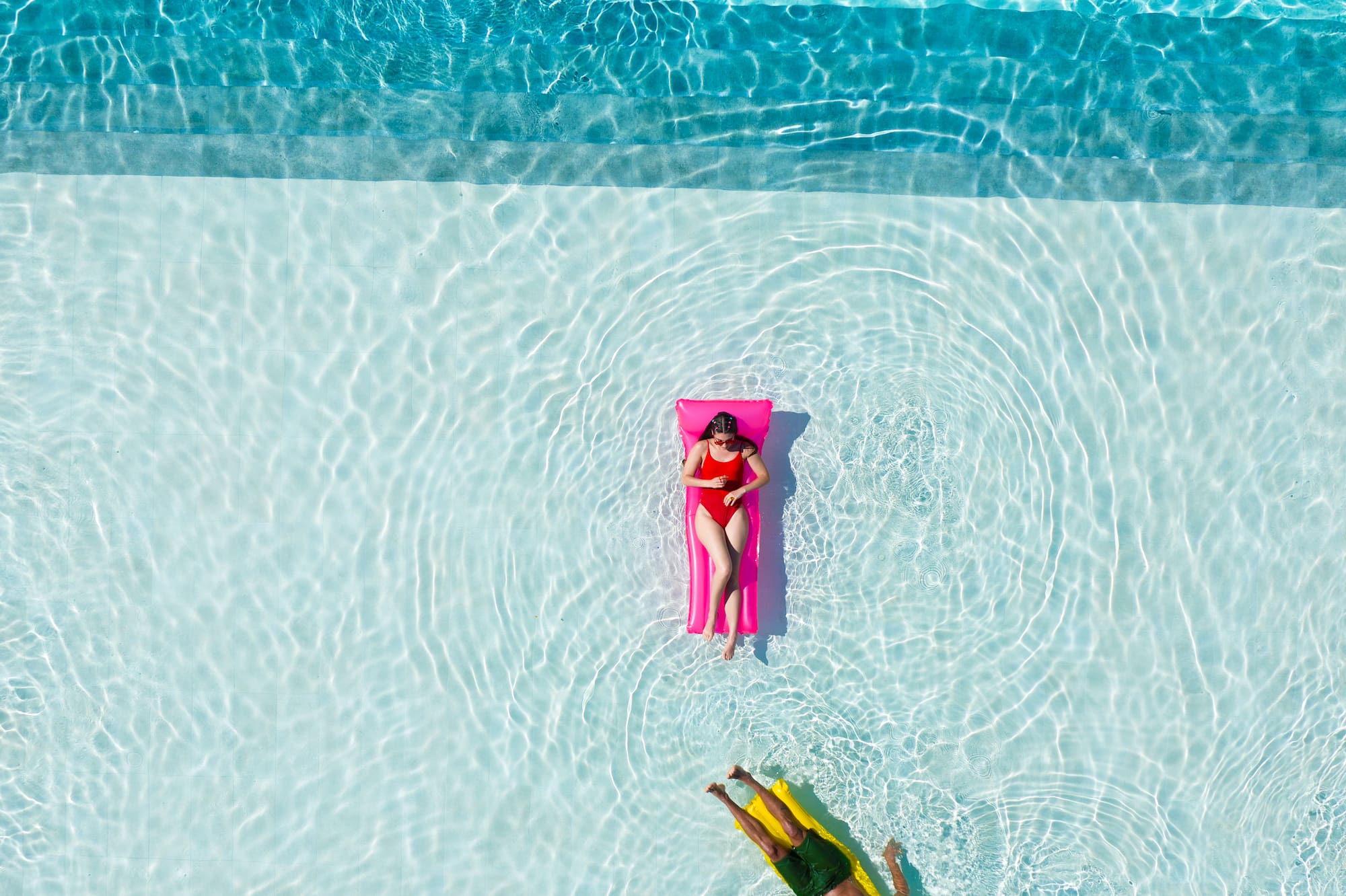 a person floating on a pink float in a pool