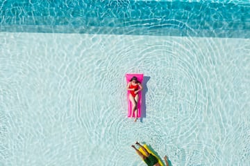 a person floating on a pink float in a pool