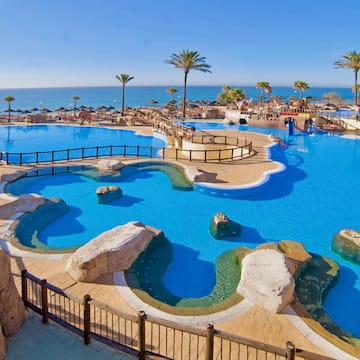 a large pool with a beach and palm trees