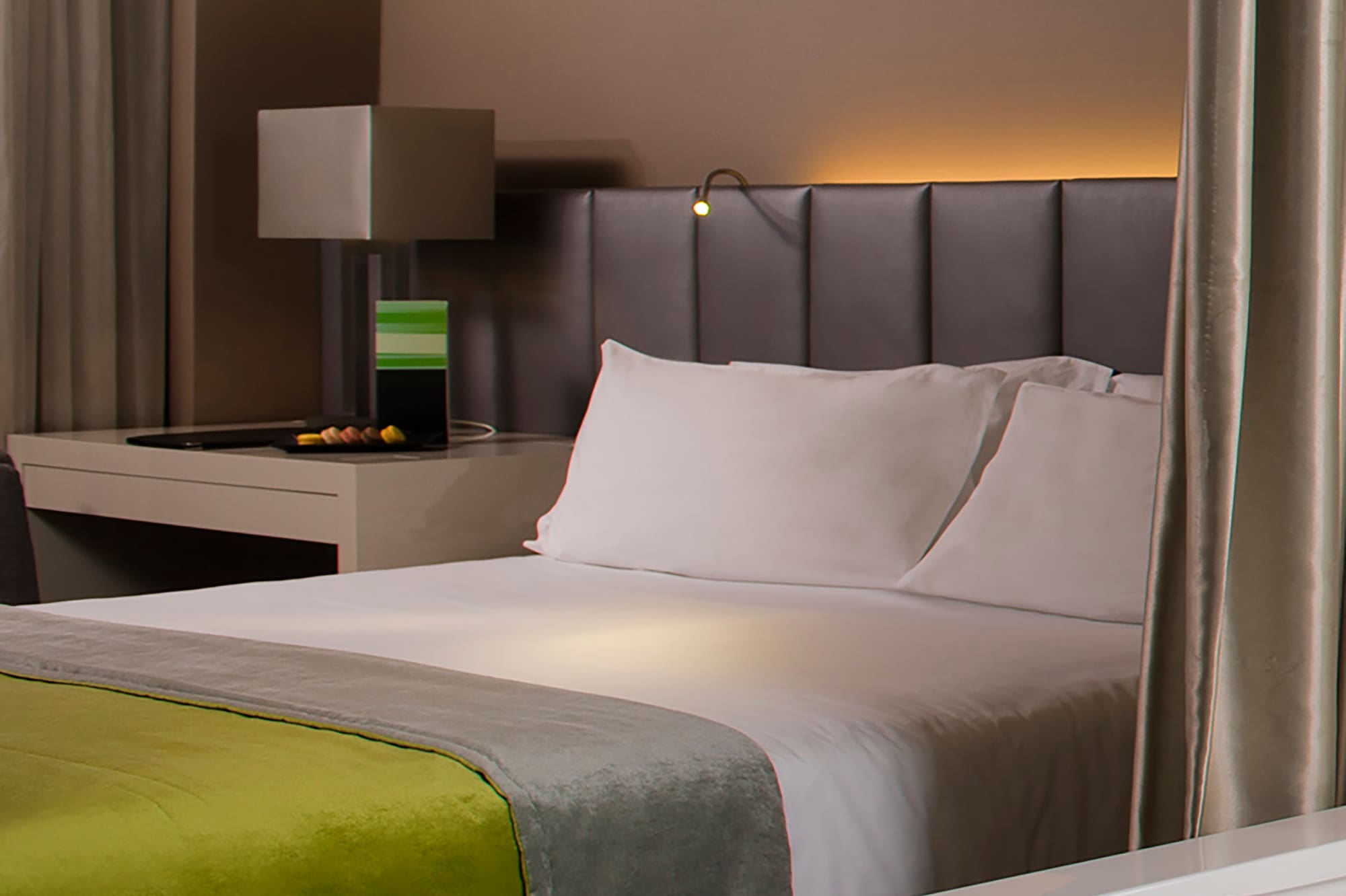 a bed with a green blanket and a white bathtub