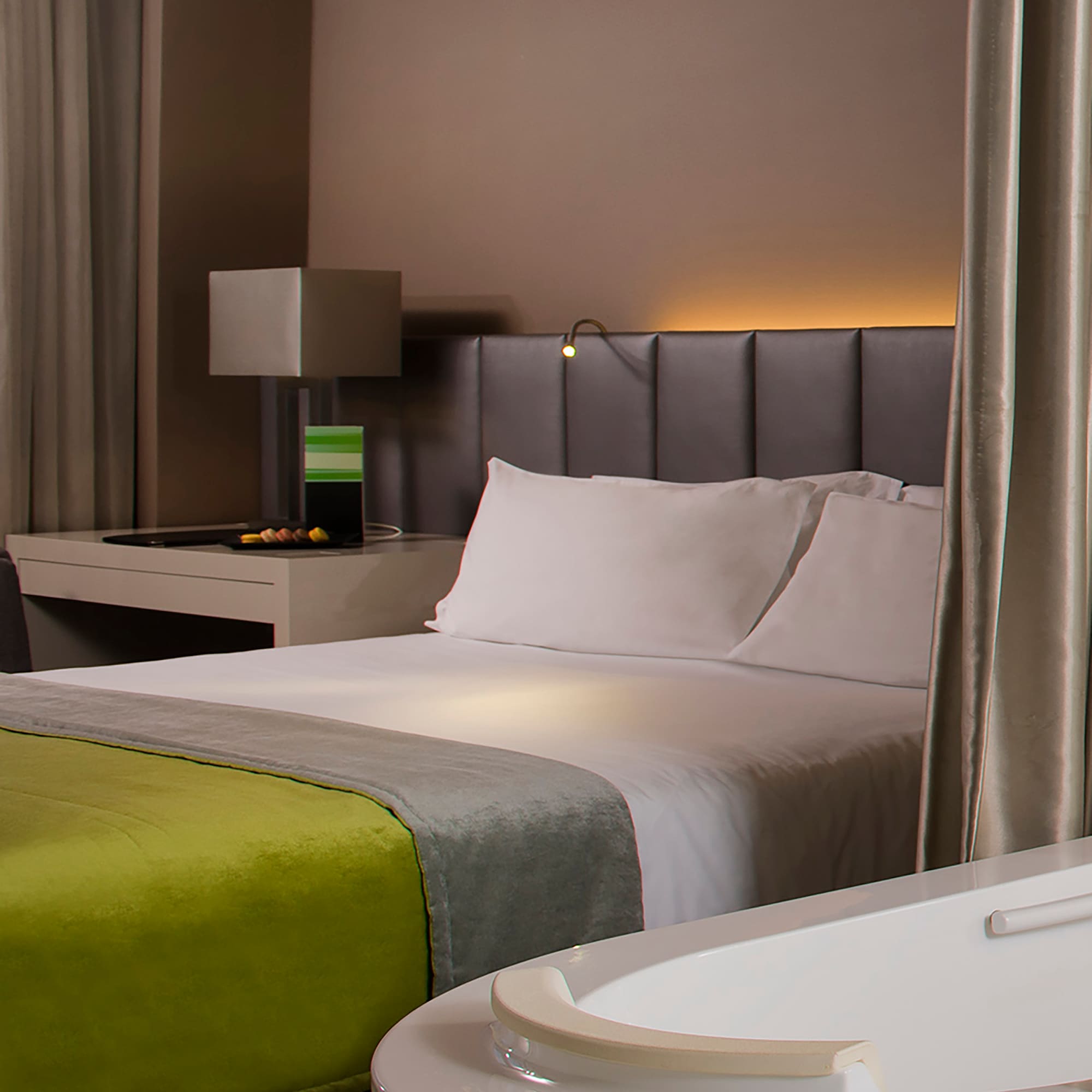 a bed with a green blanket and a white bathtub