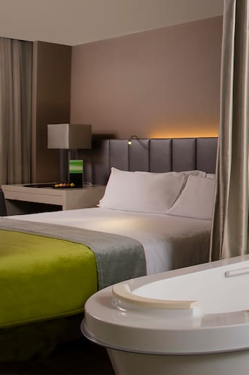 a bed with a green blanket and a white bathtub