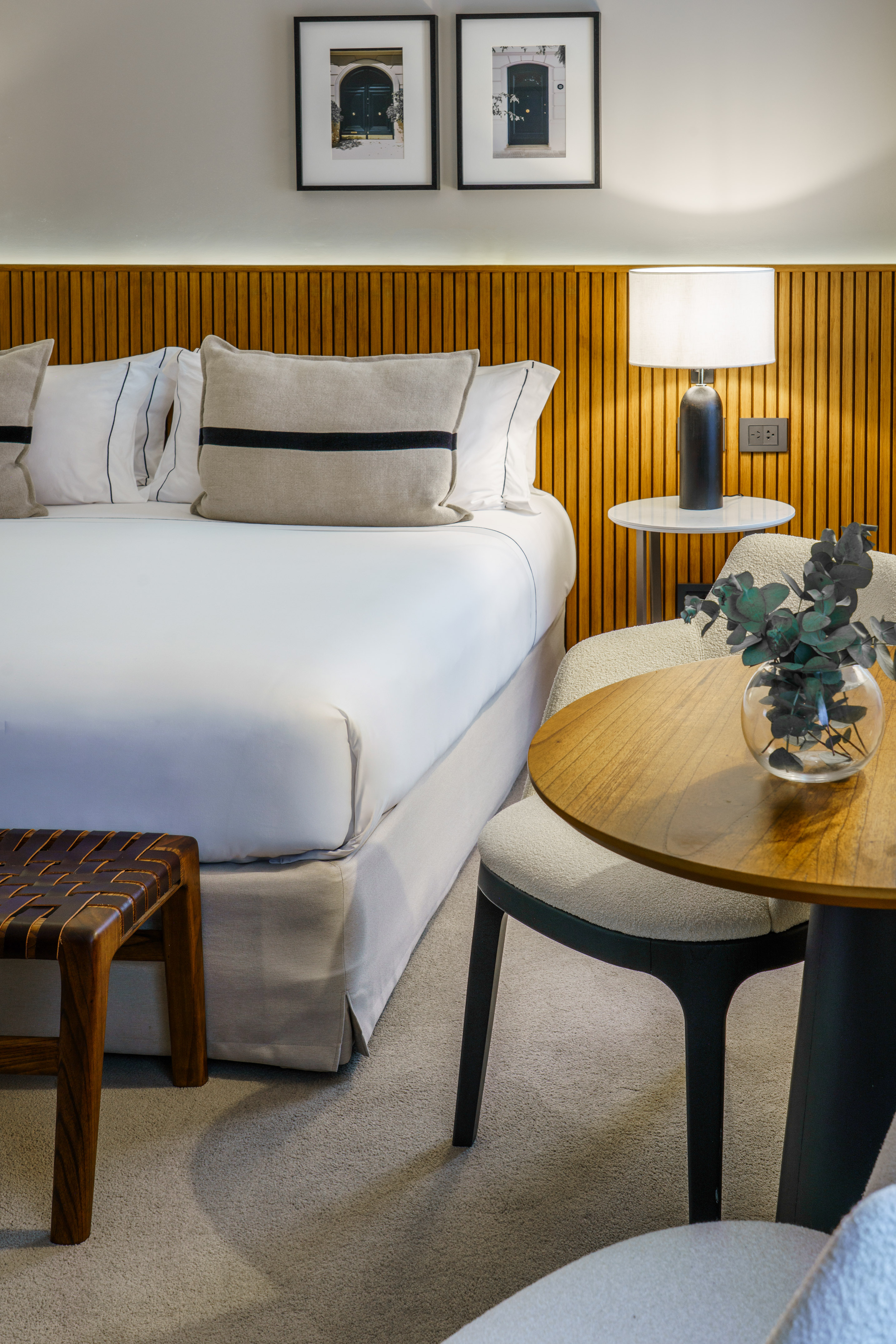 a bed with white sheets and pillows next to a table and lamp