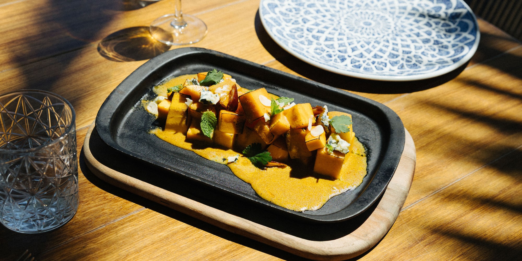 Roasted pumpkin, blue cheese, mint on black platter, restaurant dining.