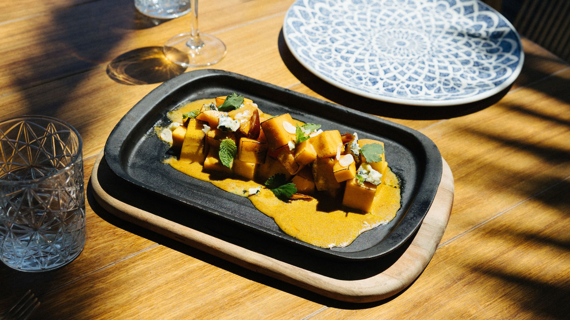 Roasted pumpkin, blue cheese, mint on black platter, restaurant dining.