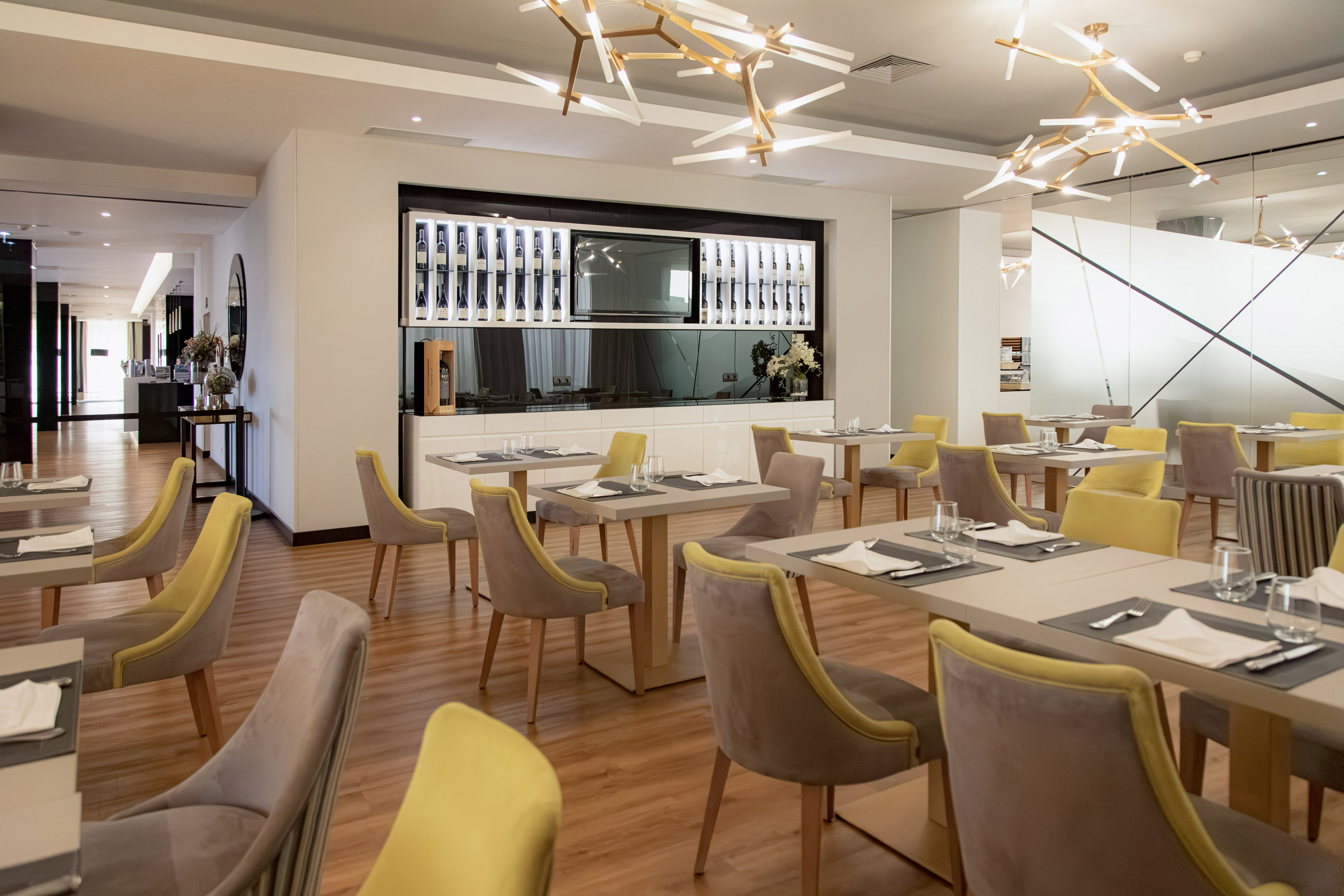 Modern restaurant dining room with elegant decor, stylish chairs, and wine display wall.