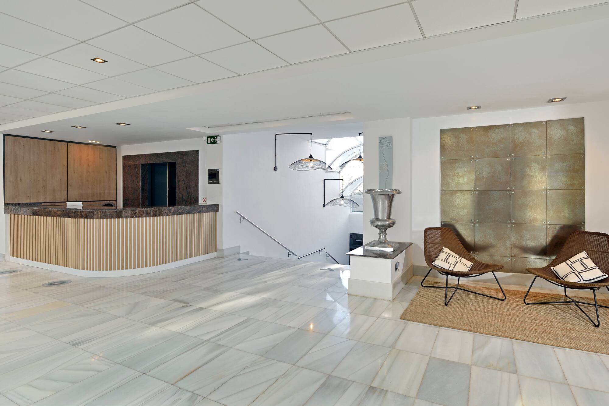 Modern hotel lobby with reception desk, marble floor, and seating area.