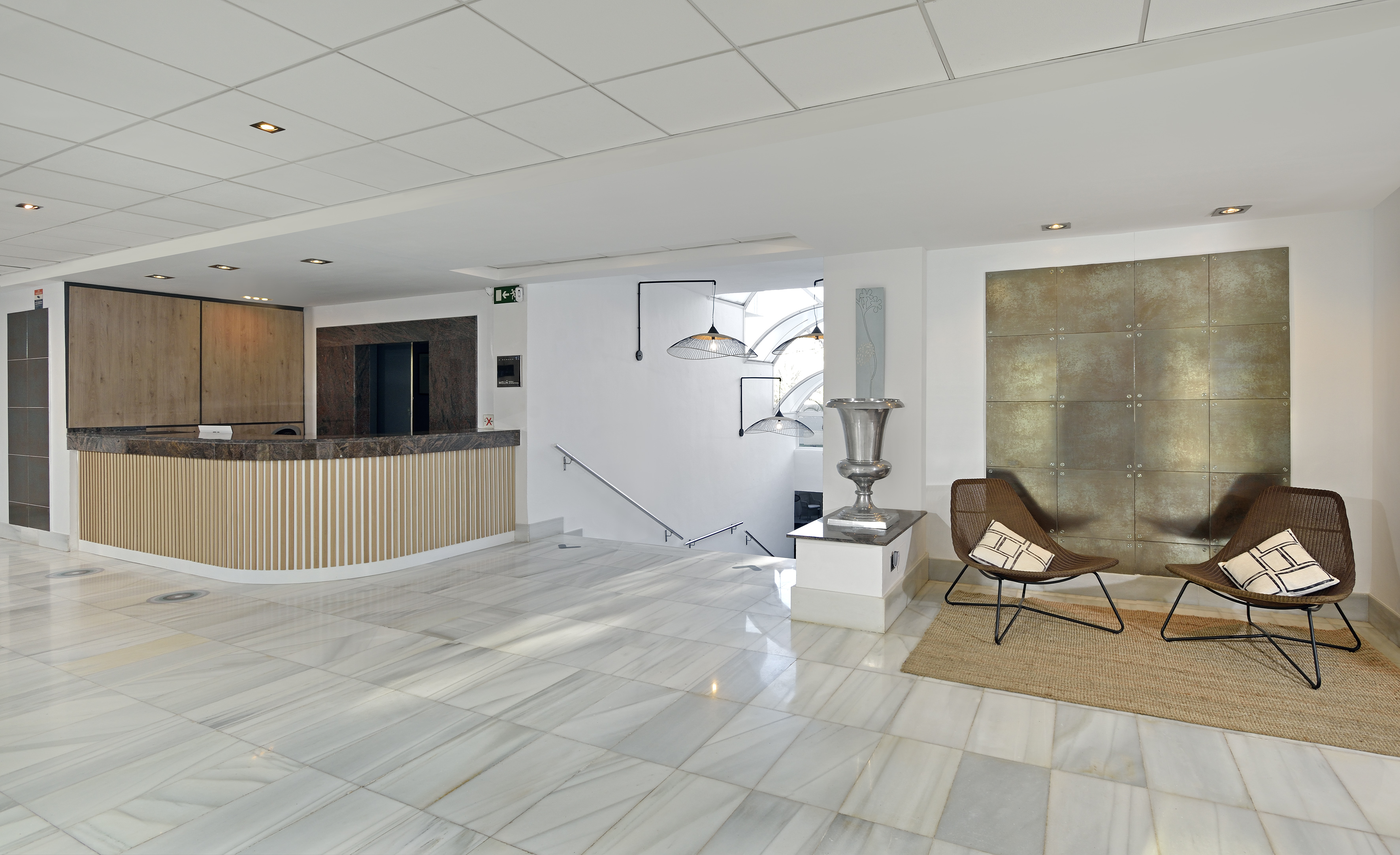 Modern hotel lobby with reception desk, marble floor, and seating area.