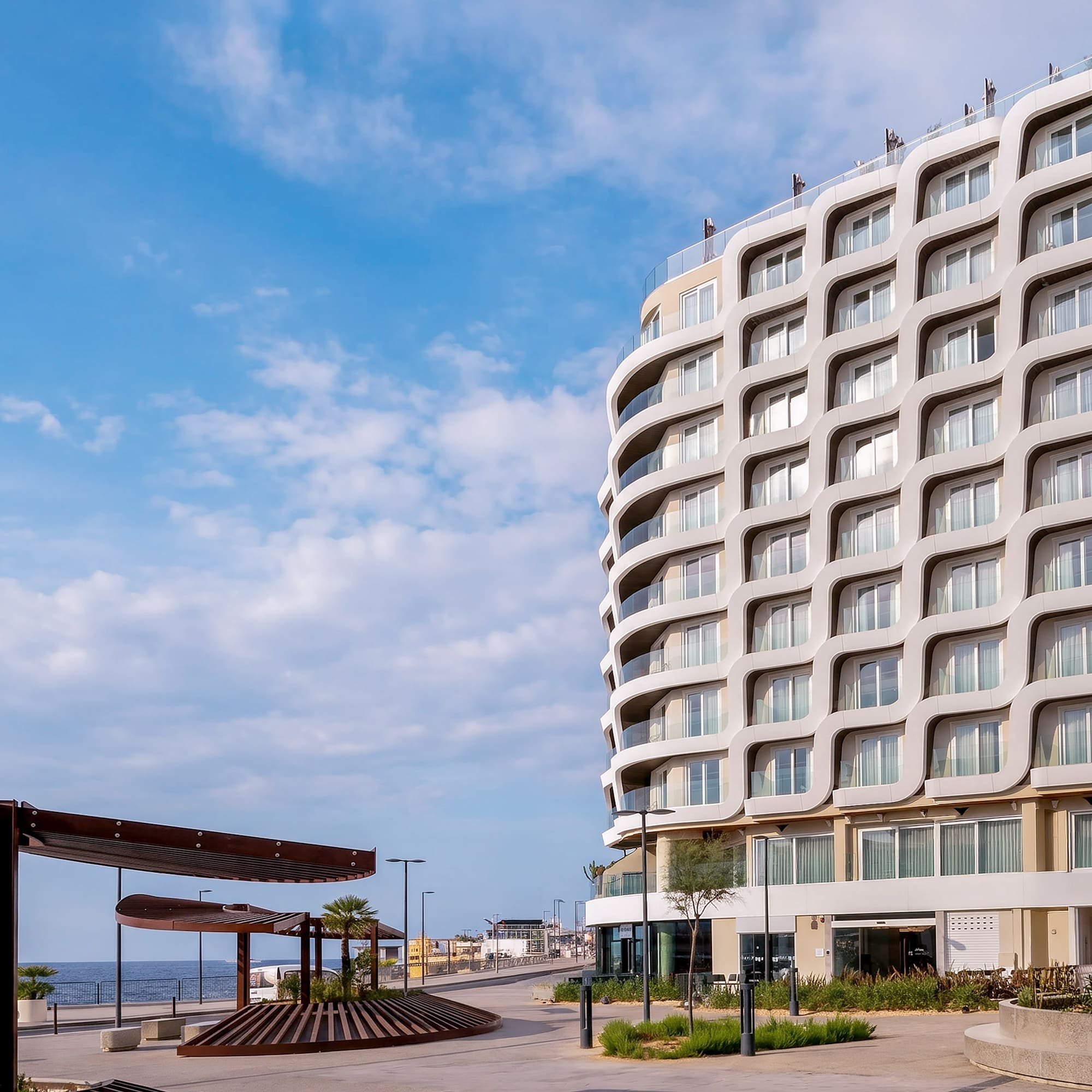 INN SIDE modern hotel with wavy facade on coastal promenade.