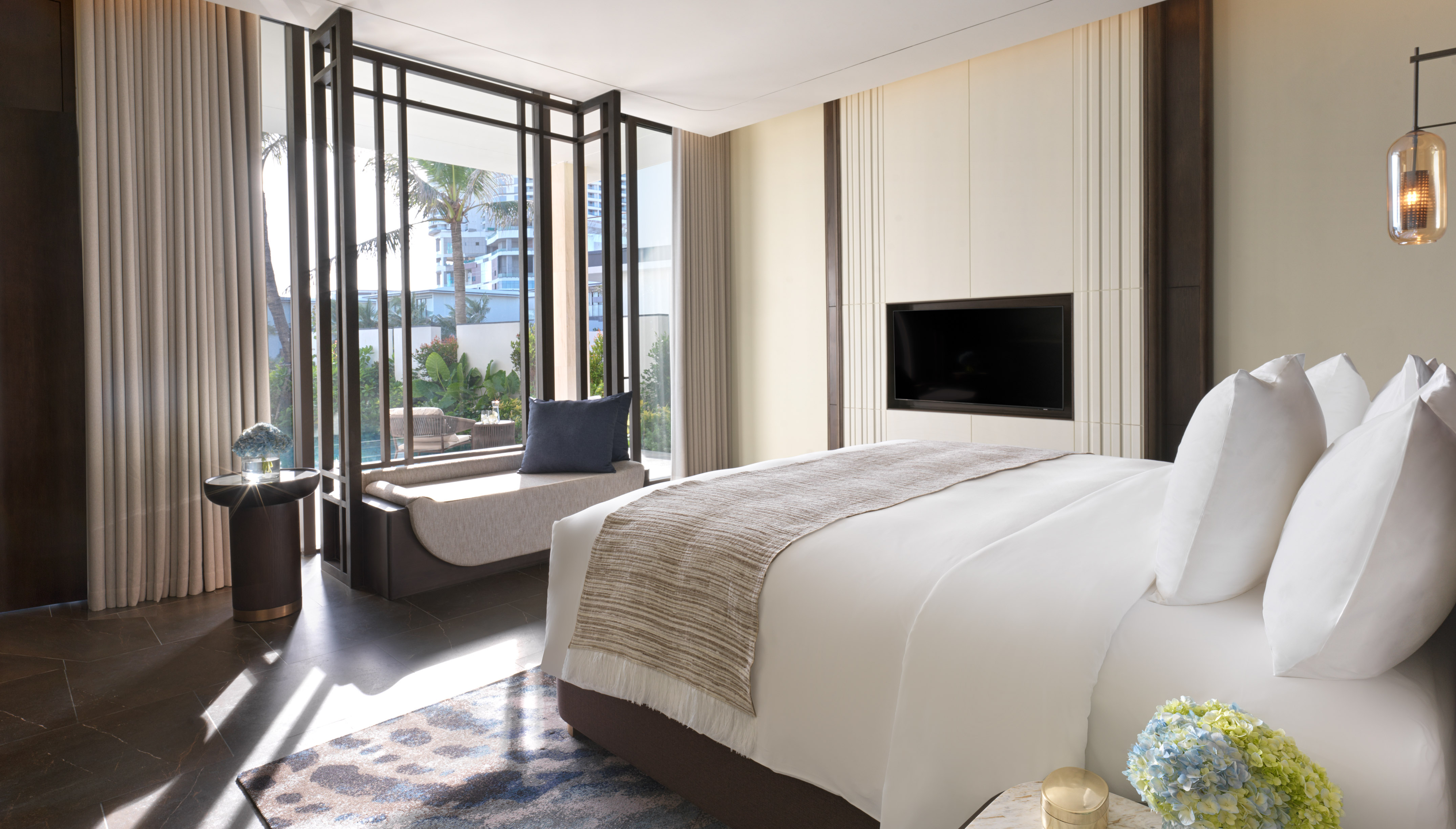 Spacious hotel bedroom with king bed, large windows, and outdoor garden view.