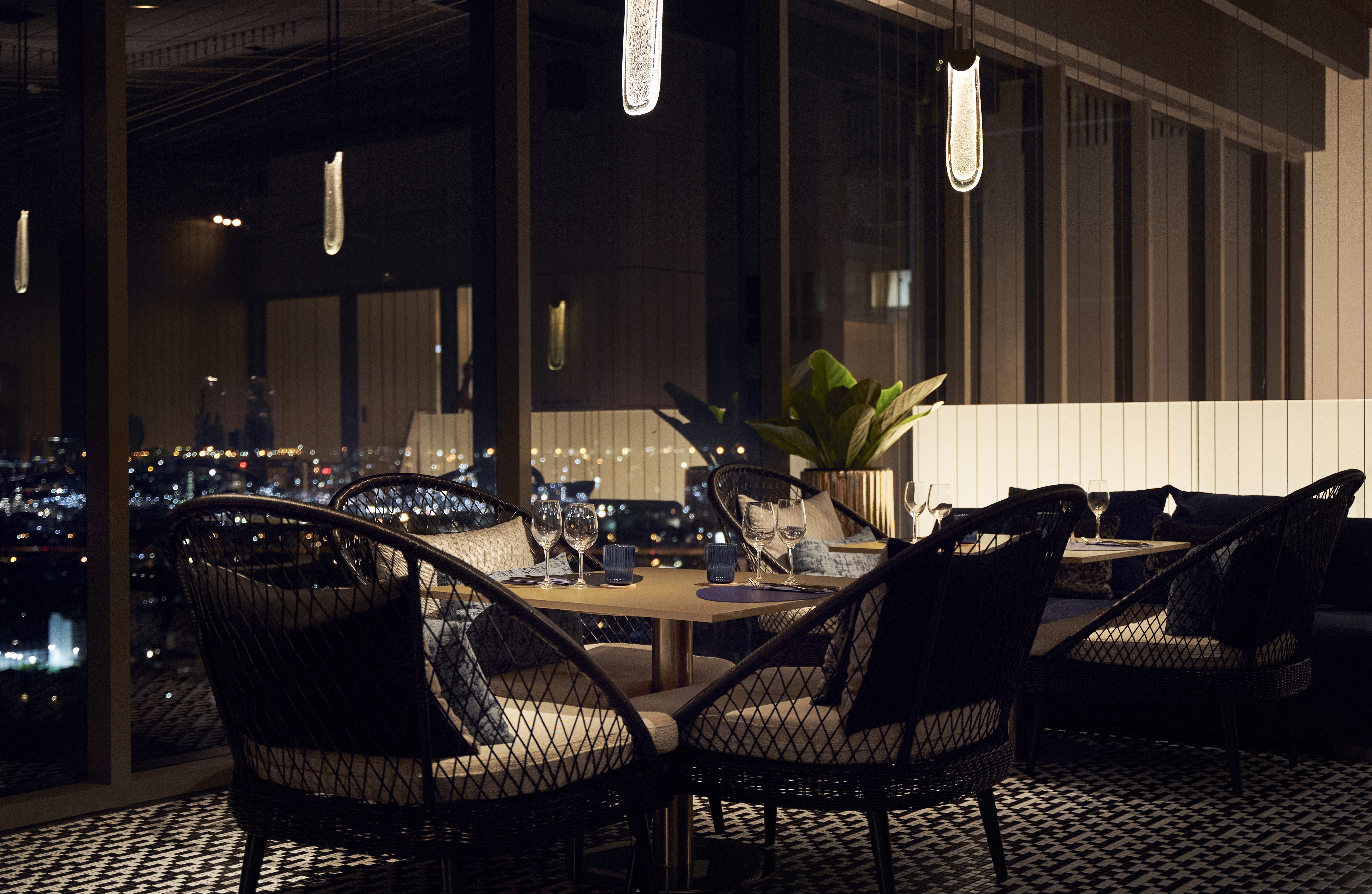 Rooftop restaurant dining with city night view and modern table setting.