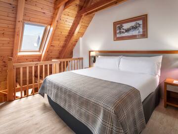 a bed in a room with a wood ceiling and a picture on the wall