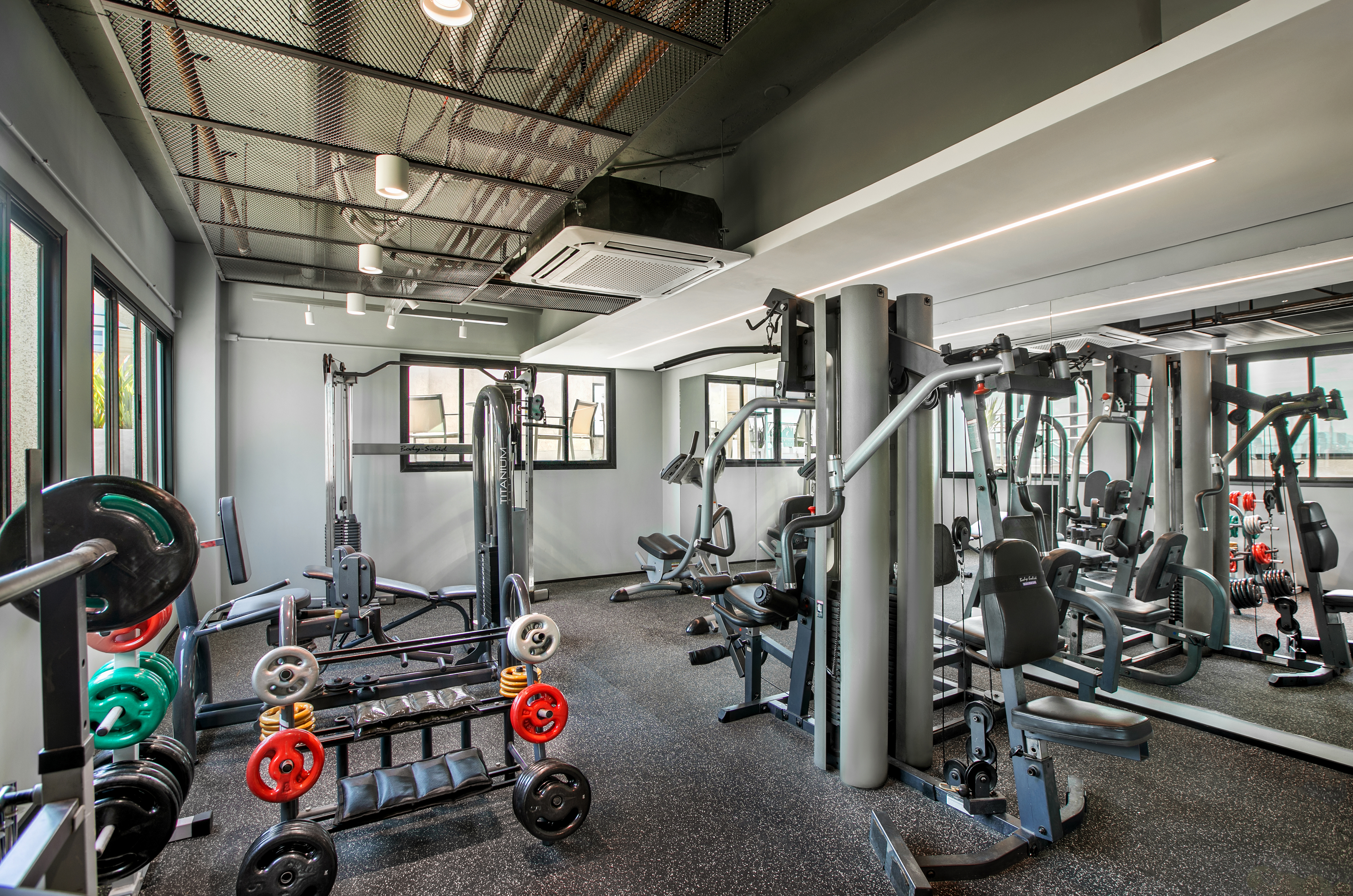 Well-lit modern gym with weight machines, free weights, and speckled rubber floor.