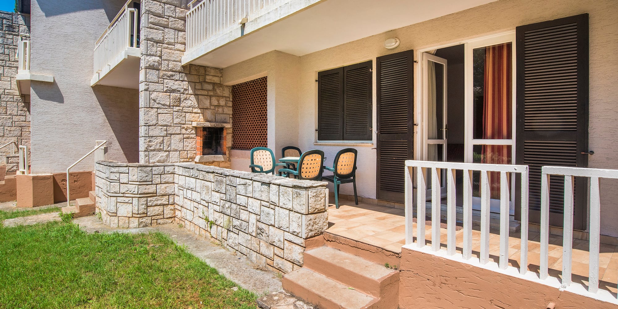 a patio with chairs and a stone wall