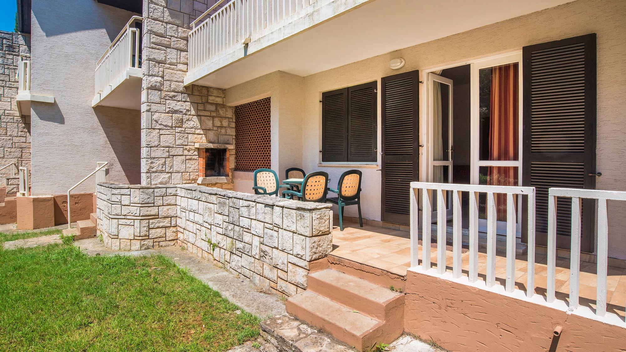 a patio with chairs and a stone wall