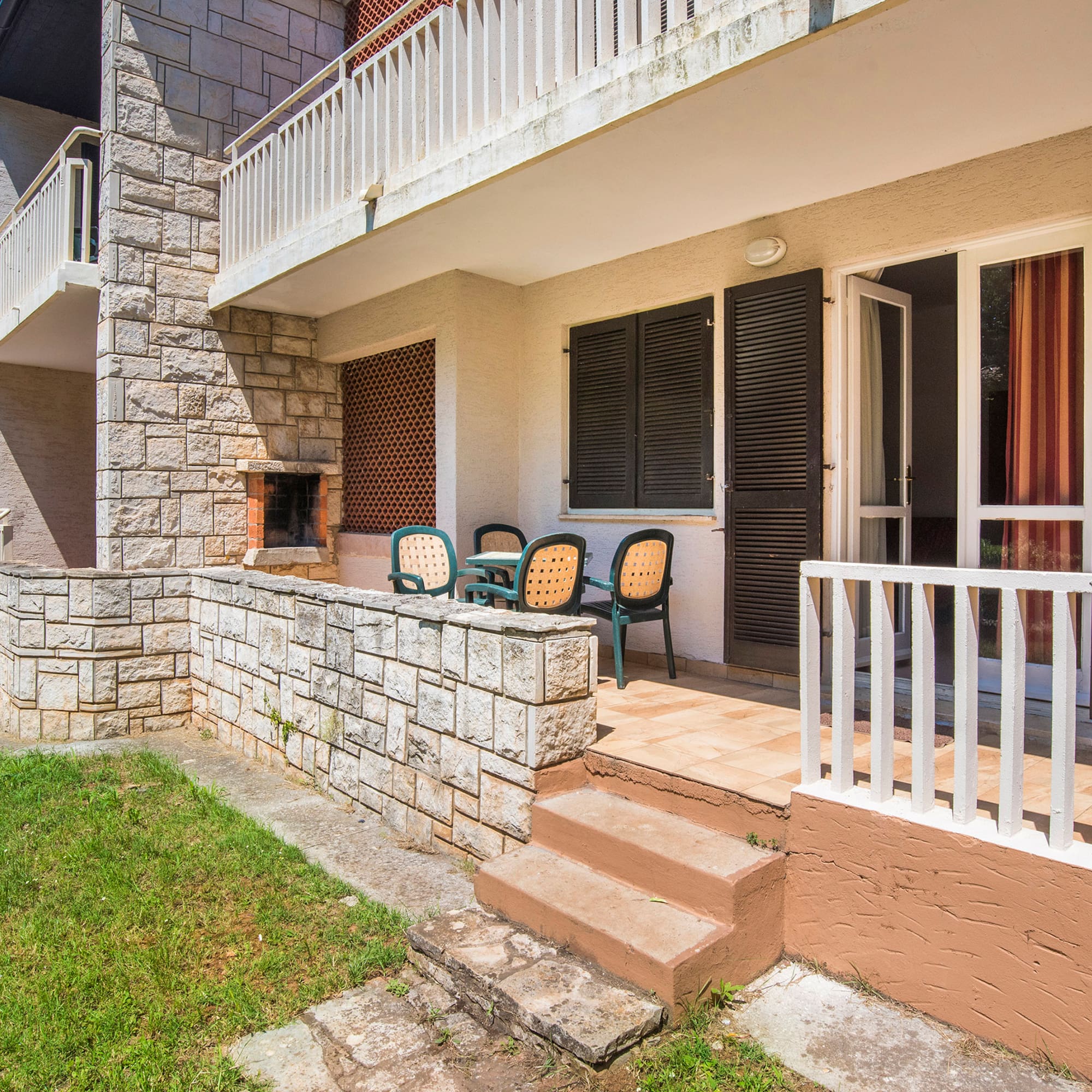 a patio with chairs and a stone wall
