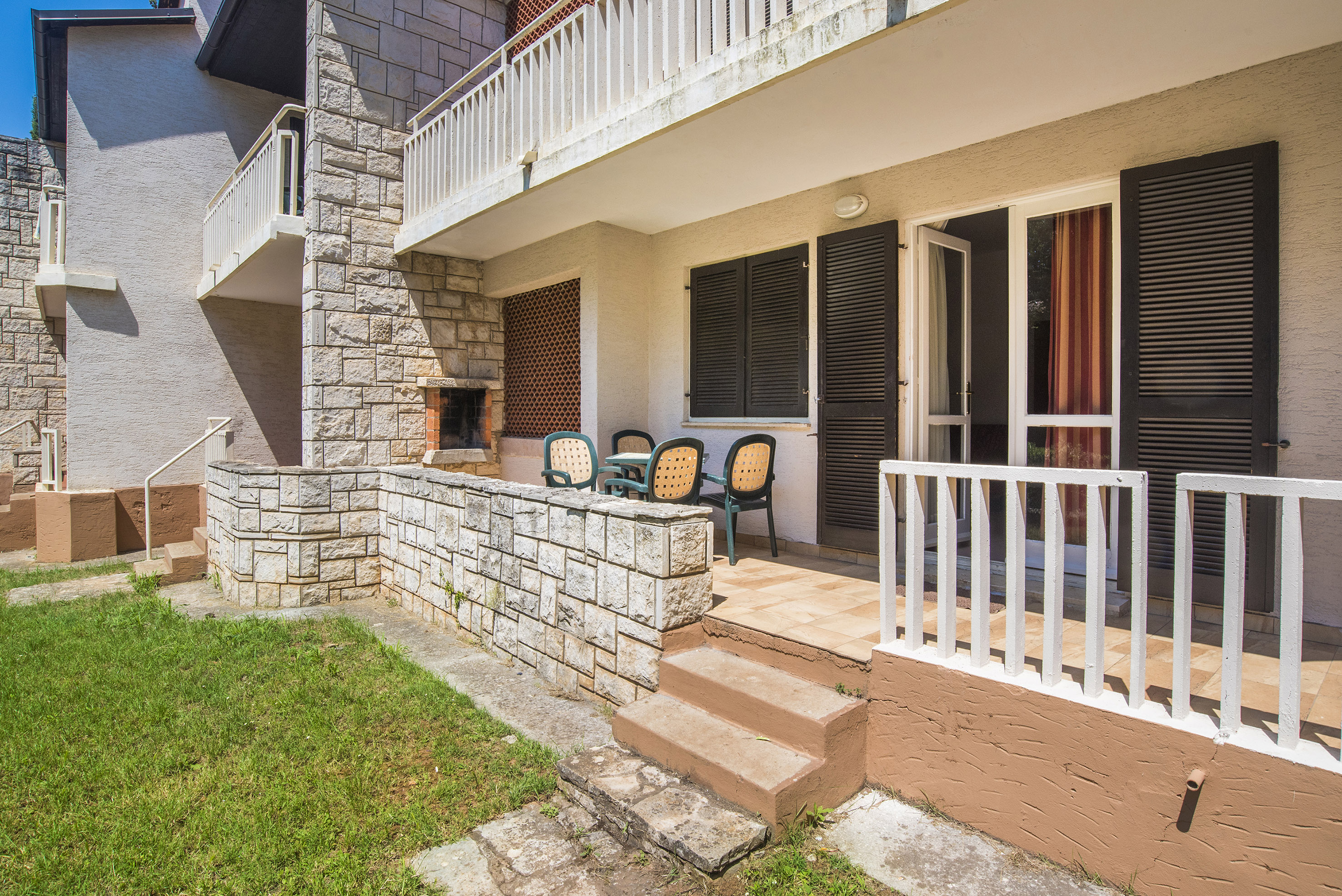 a patio with chairs and a stone wall