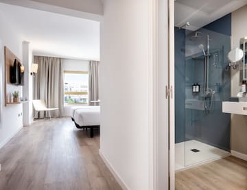 a bathroom with a glass shower and a bed