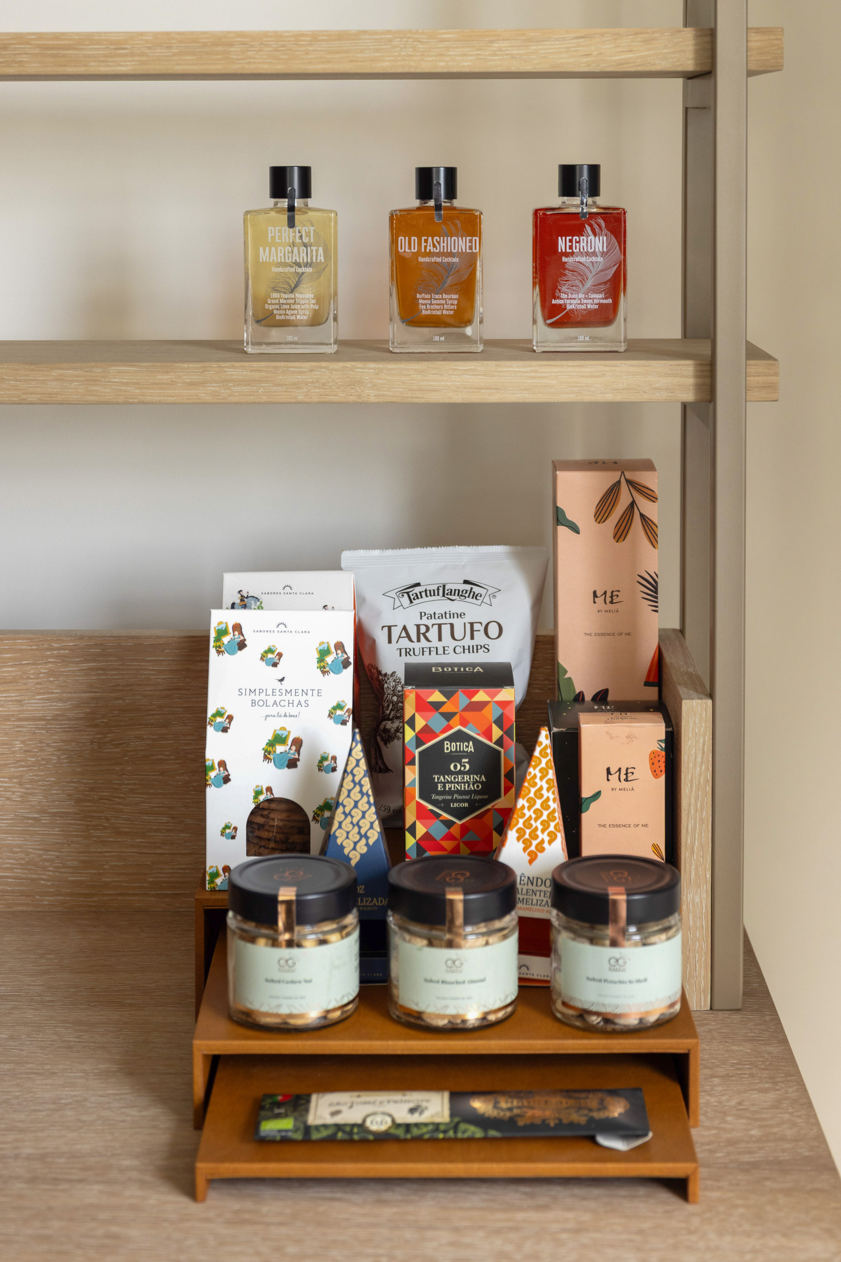 Hotel minibar with gourmet cocktails, truffle chips, and assorted snacks.