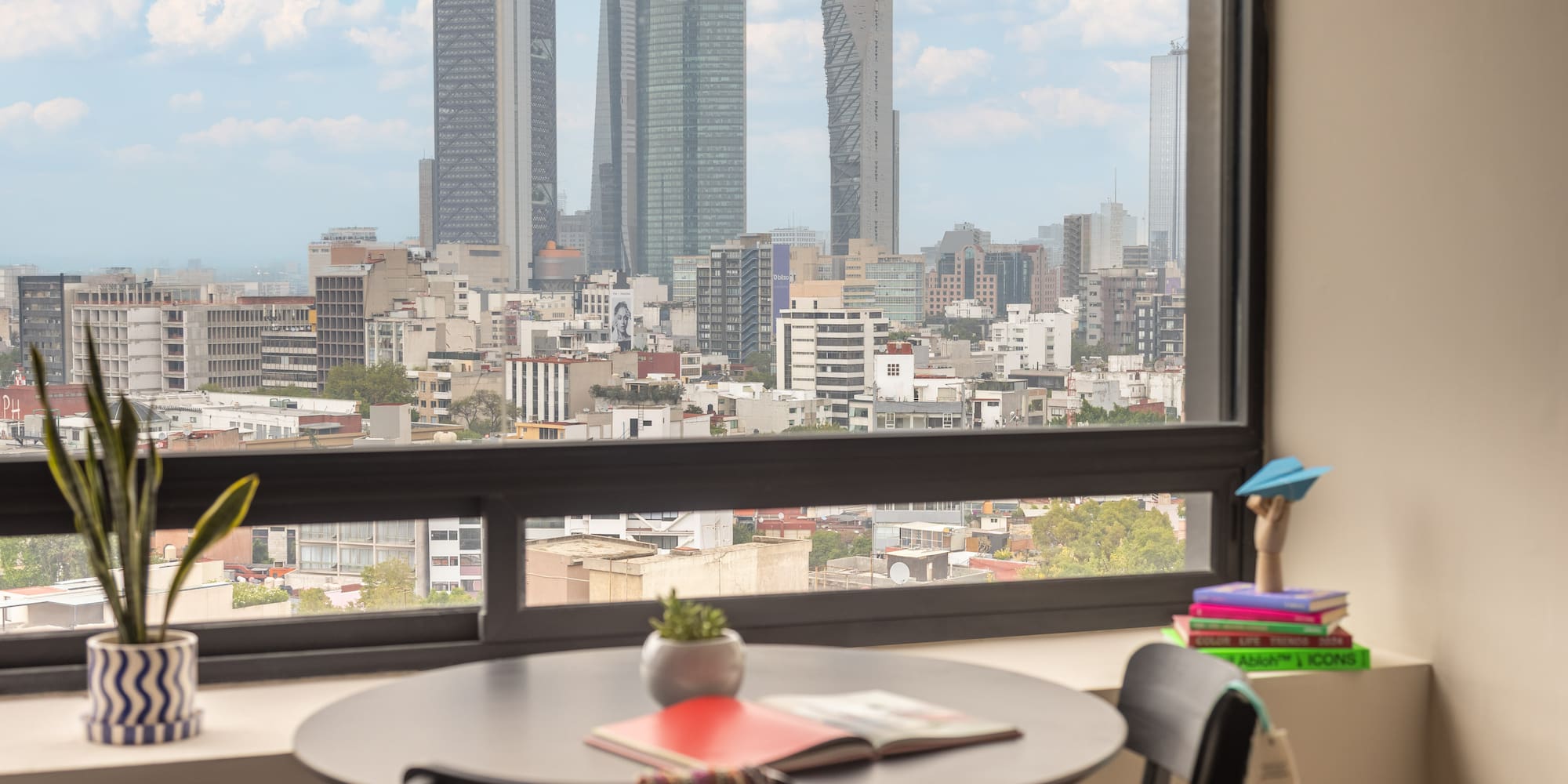 Modern apartment overlooking Mexico City skyline with prominent skyscrapers.