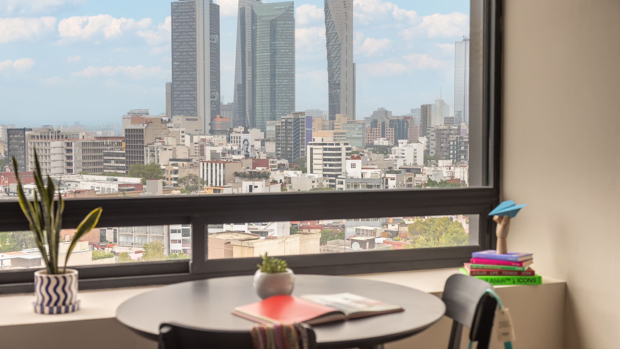 Modern apartment overlooking Mexico City skyline with prominent skyscrapers.