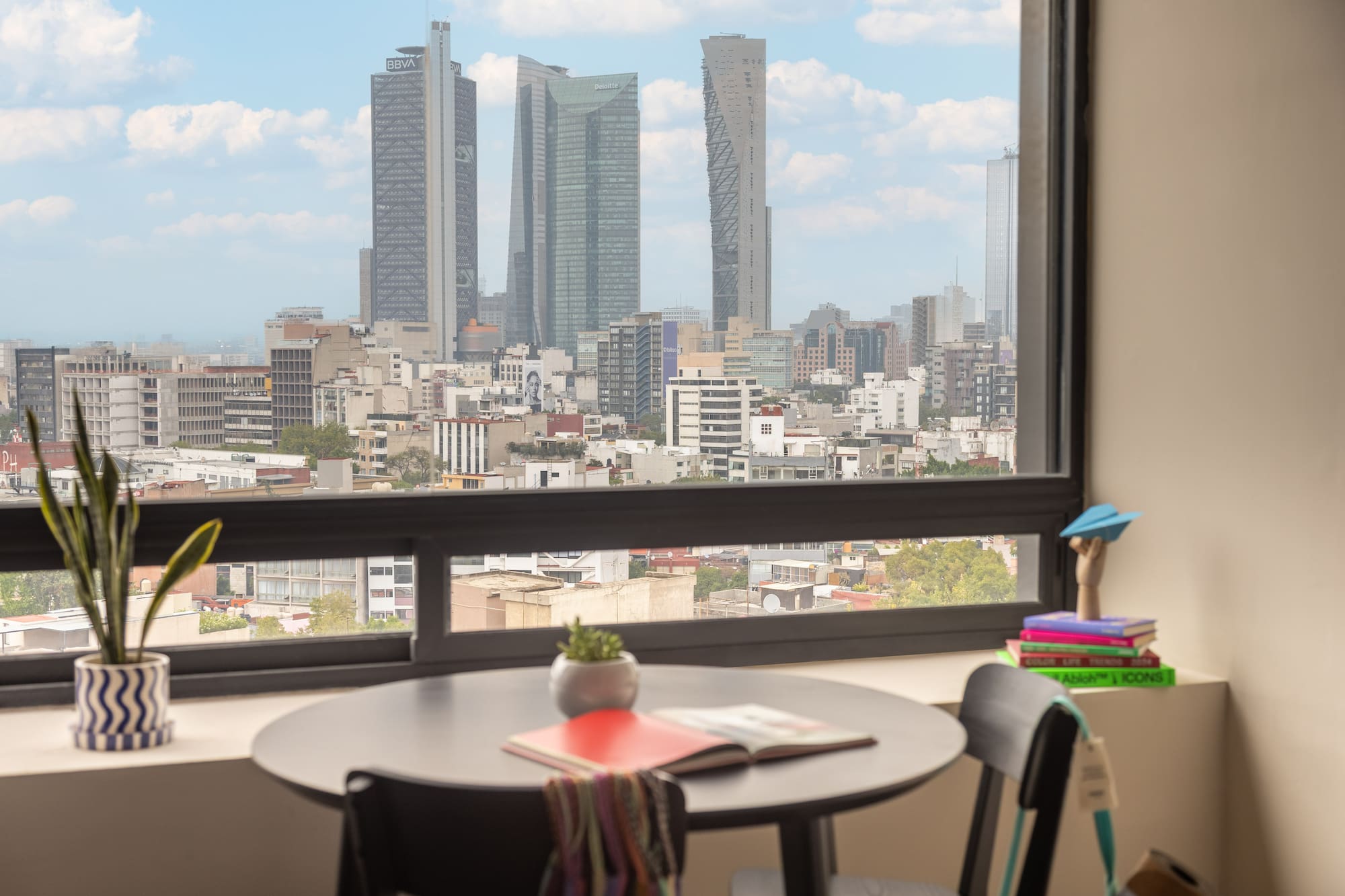 Modern apartment overlooking Mexico City skyline with prominent skyscrapers.