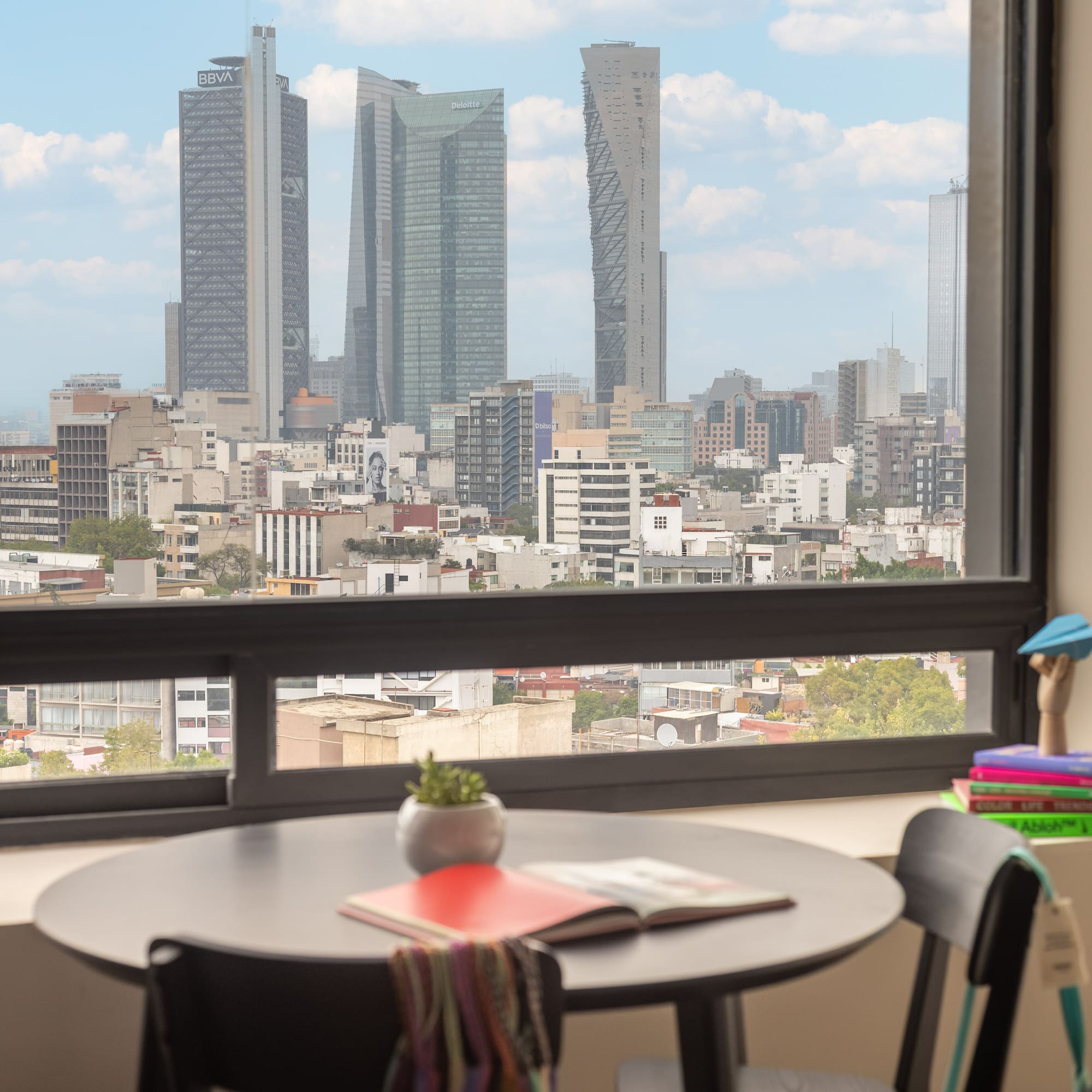 Modern apartment overlooking Mexico City skyline with prominent skyscrapers.