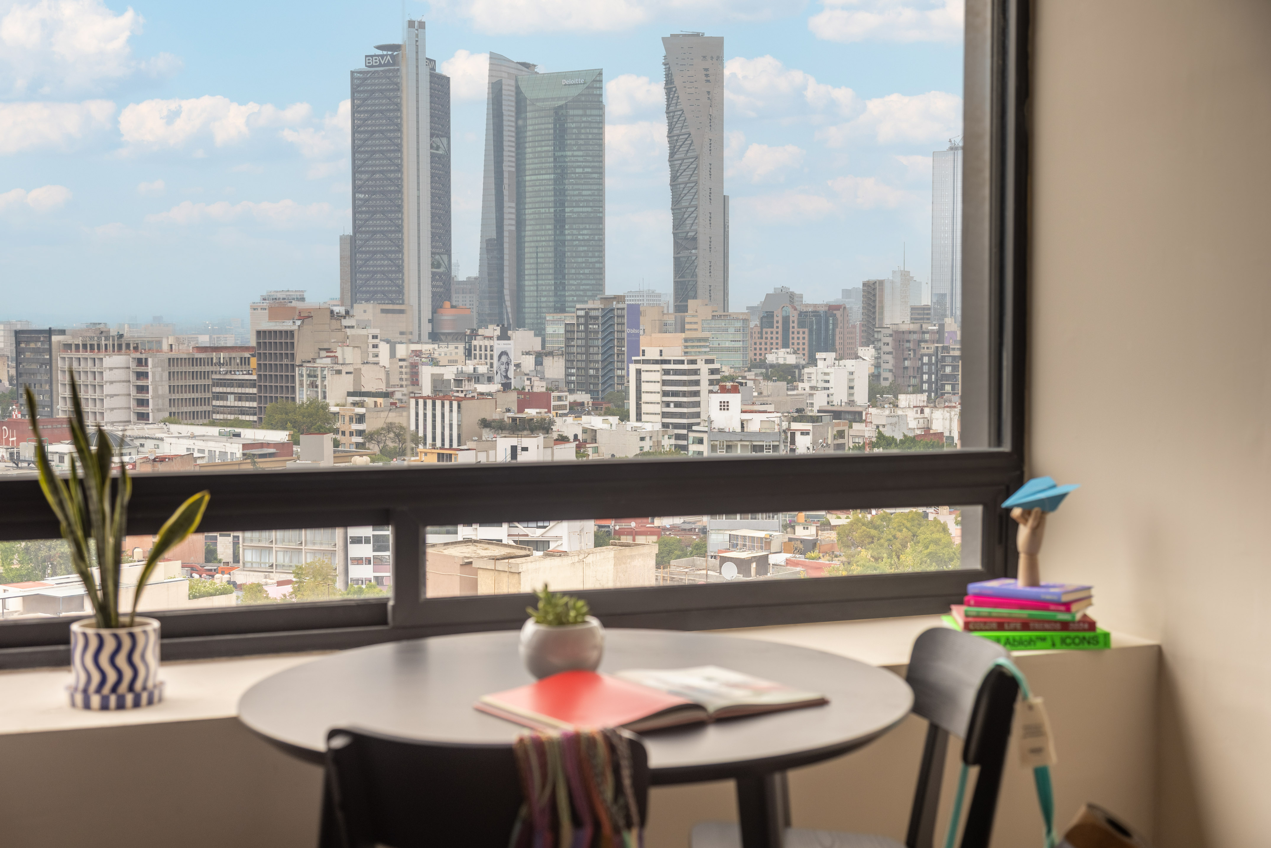 Modern apartment overlooking Mexico City skyline with prominent skyscrapers.