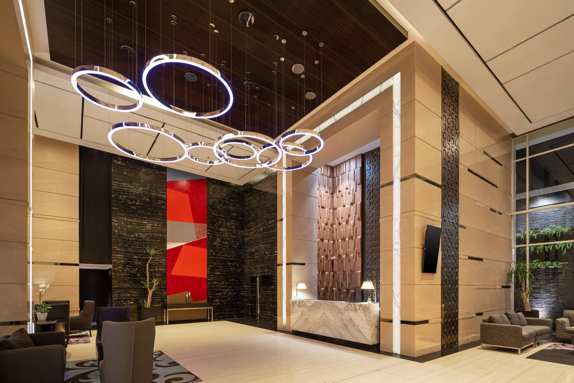 Modern luxury hotel lobby with marble reception and circular chandeliers.