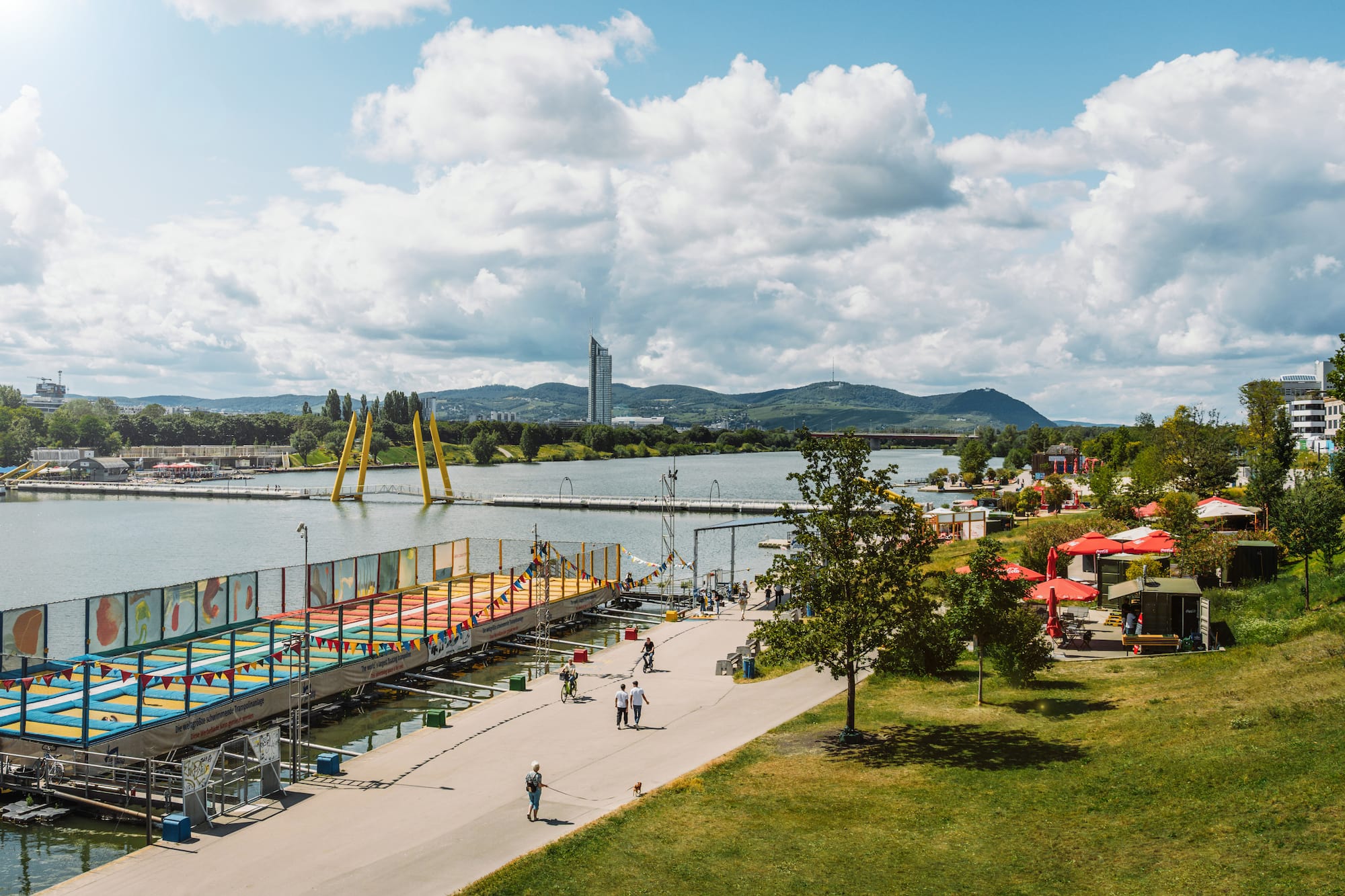 Vienna's Danube Island waterfront with a floating trampoline park and city skyline.